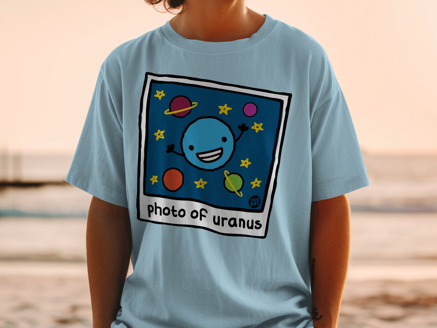 T-shirt with cartoon drawing of a smiling planet Uranus and stars.