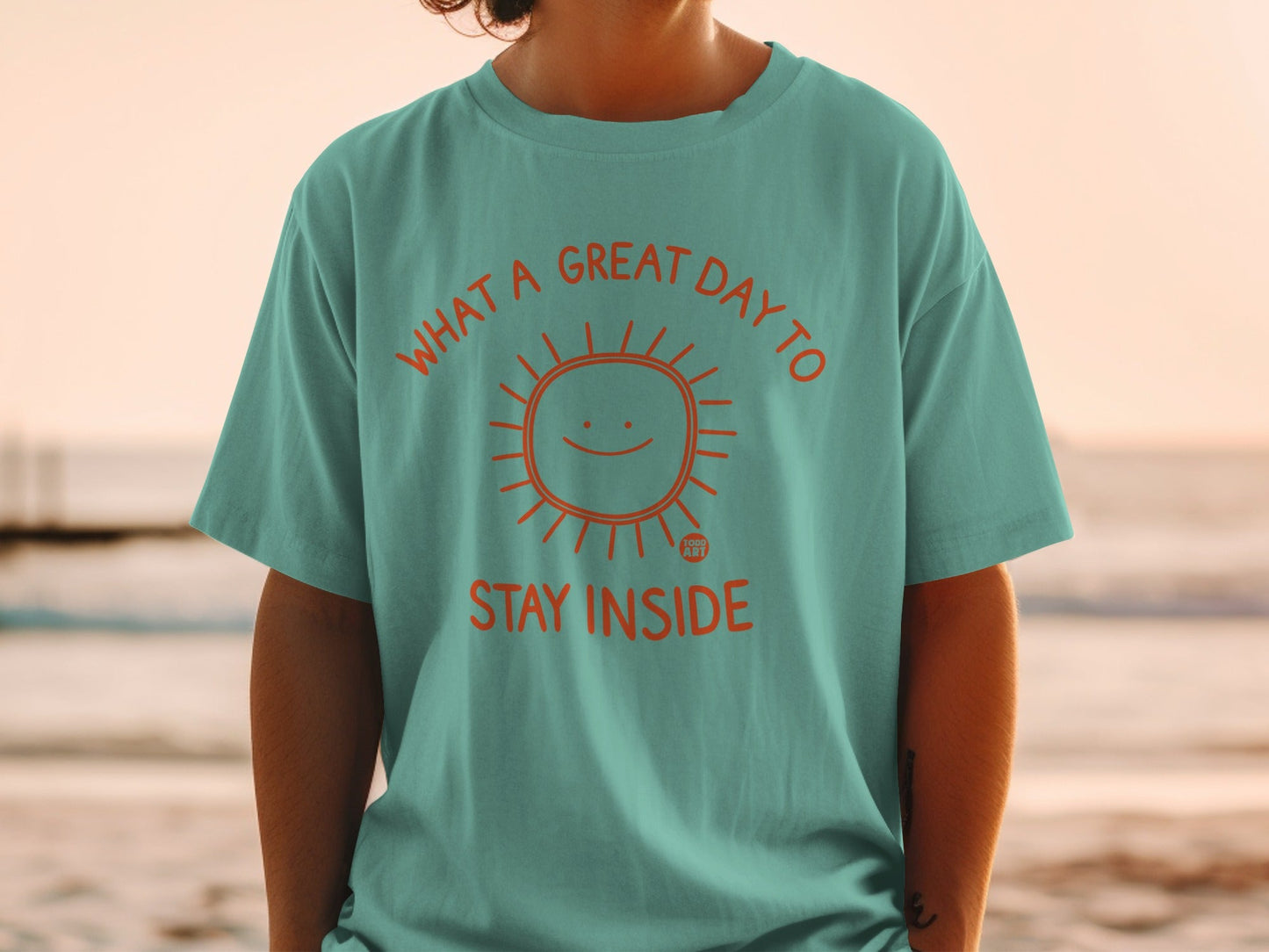 Teal t-shirt with orange sun graphic and text "WHAT A GREAT DAY TO STAY INSIDE".