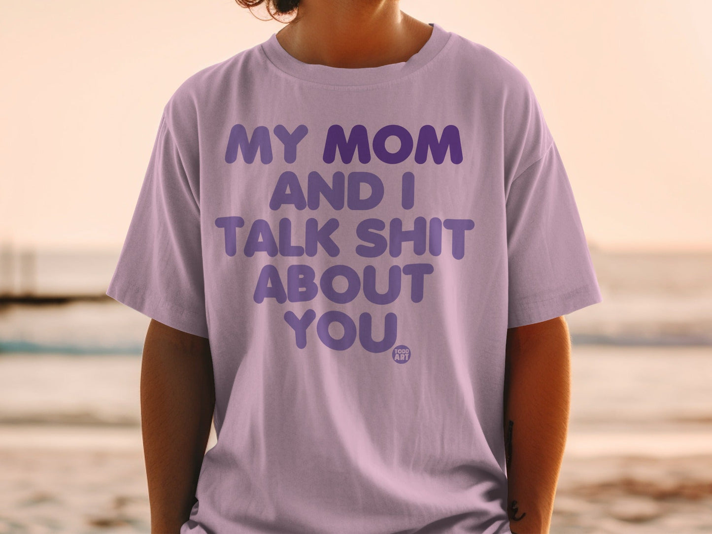 Lavender t-shirt with bold purple text reading "MY MOM AND I TALK SHIT ABOUT YOU".
