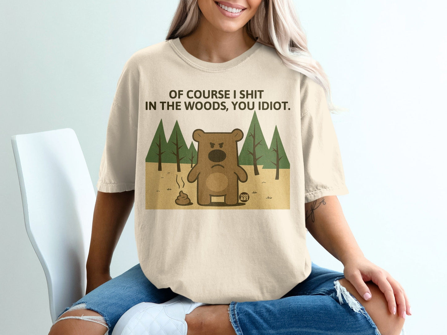 Cream t-shirt with cartoon bear graphic and text "Of course I shit in the woods, you idiot."