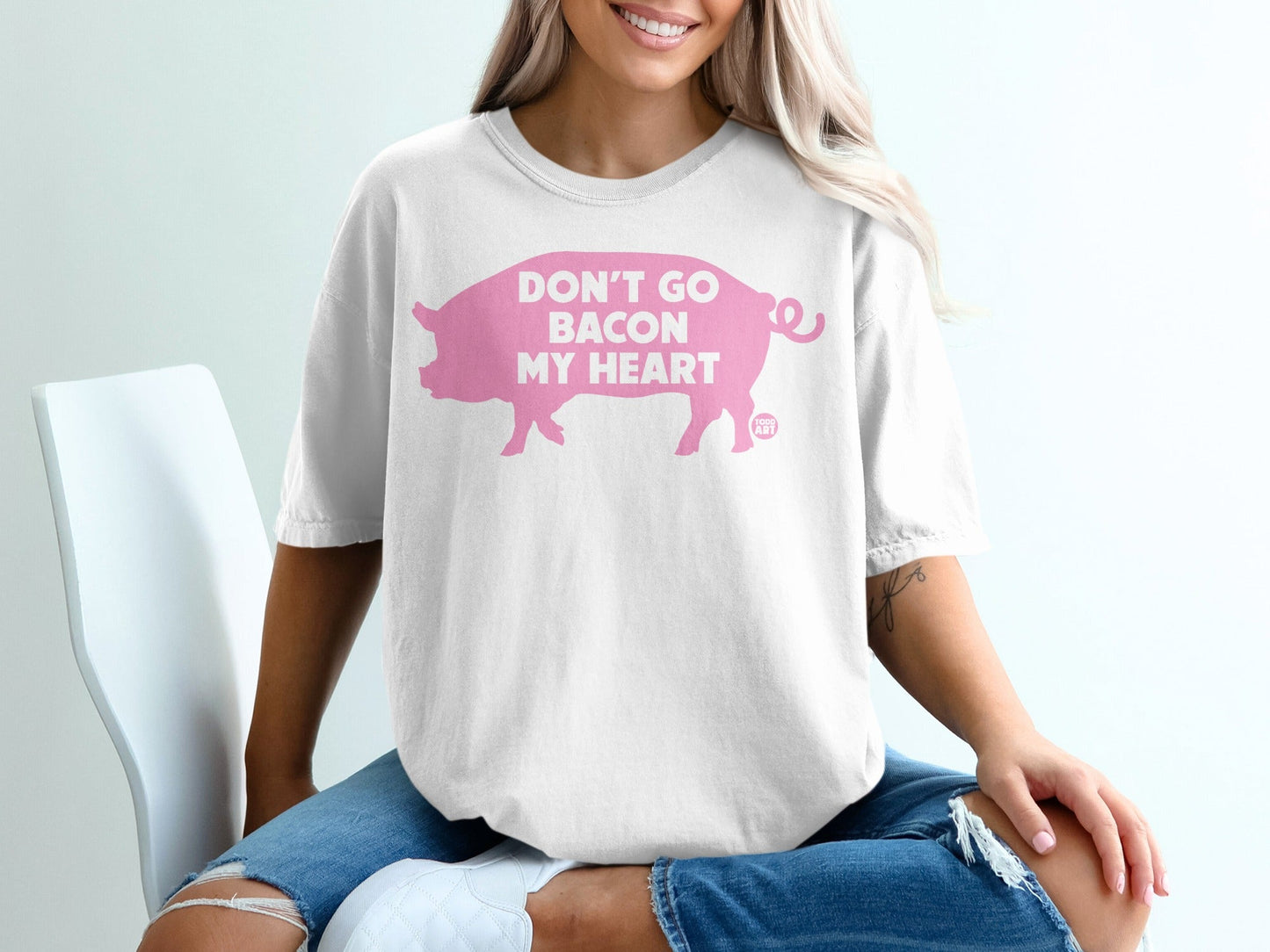 White t-shirt with pink text and pig graphic that reads "Don't Go Bacon My Heart".