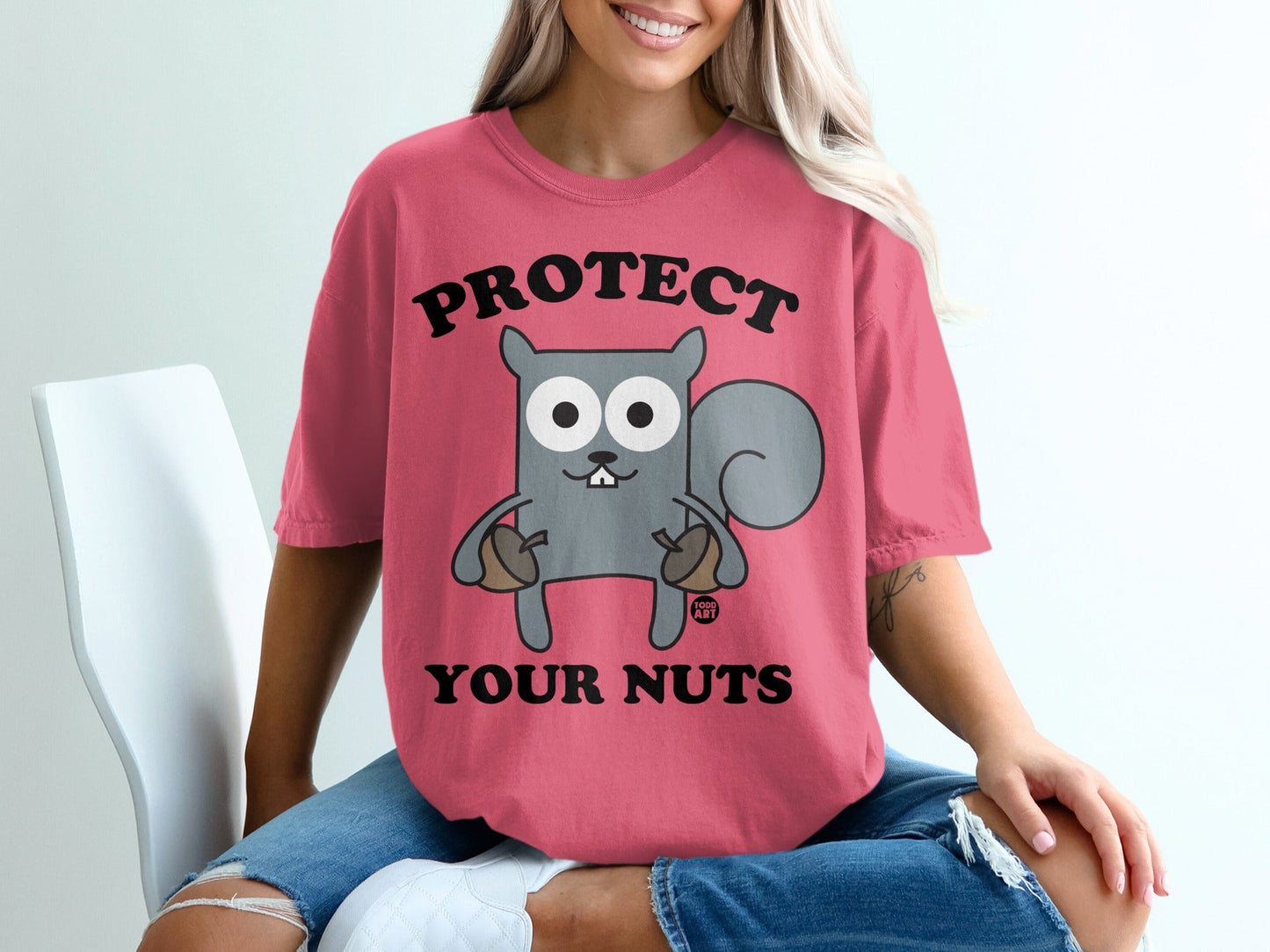 Pink t-shirt with cartoon squirrel and text "PROTECT YOUR NUTS".