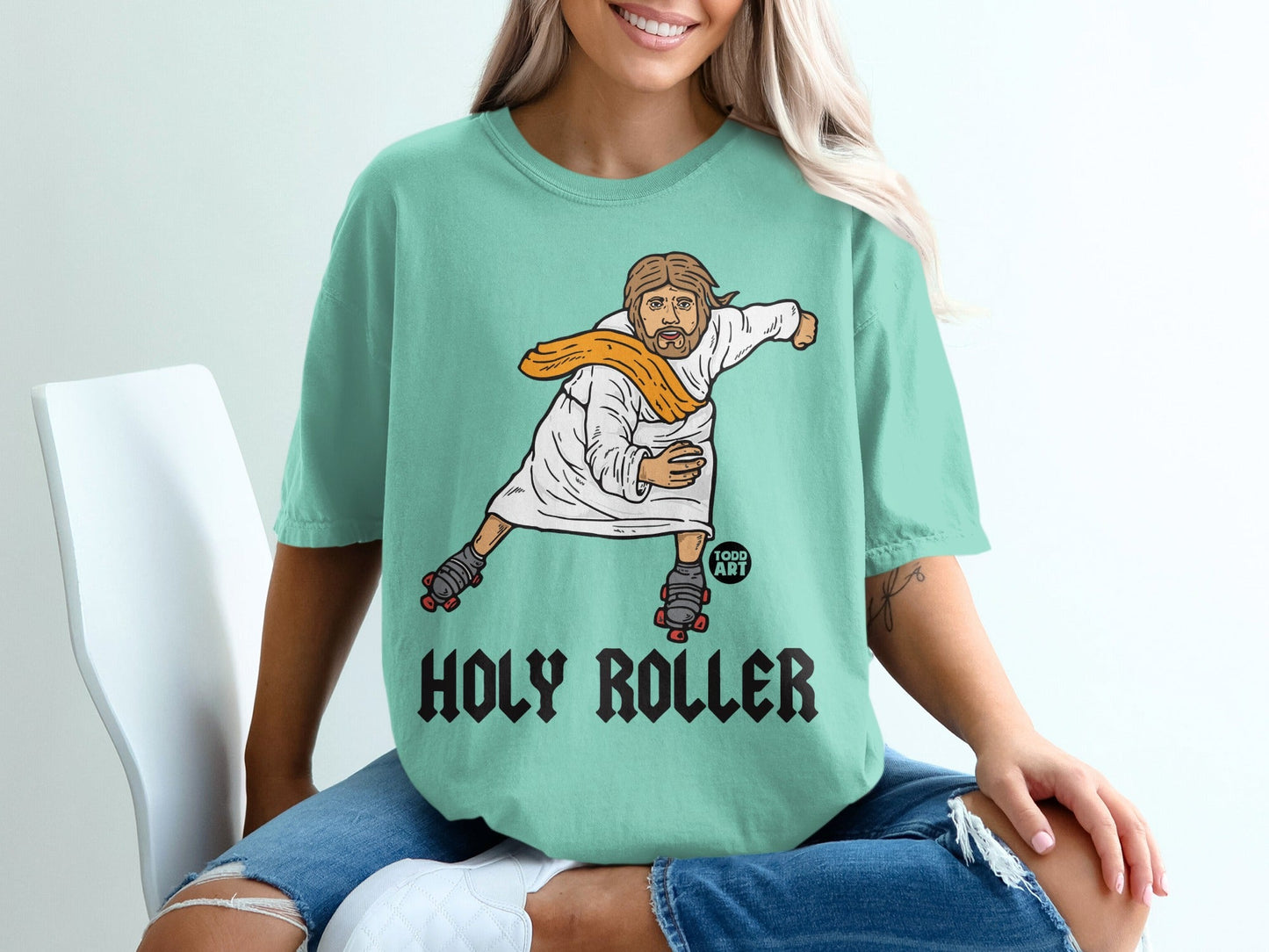 Jesus on roller skates wearing a white robe and orange scarf, text "HOLY ROLLER".