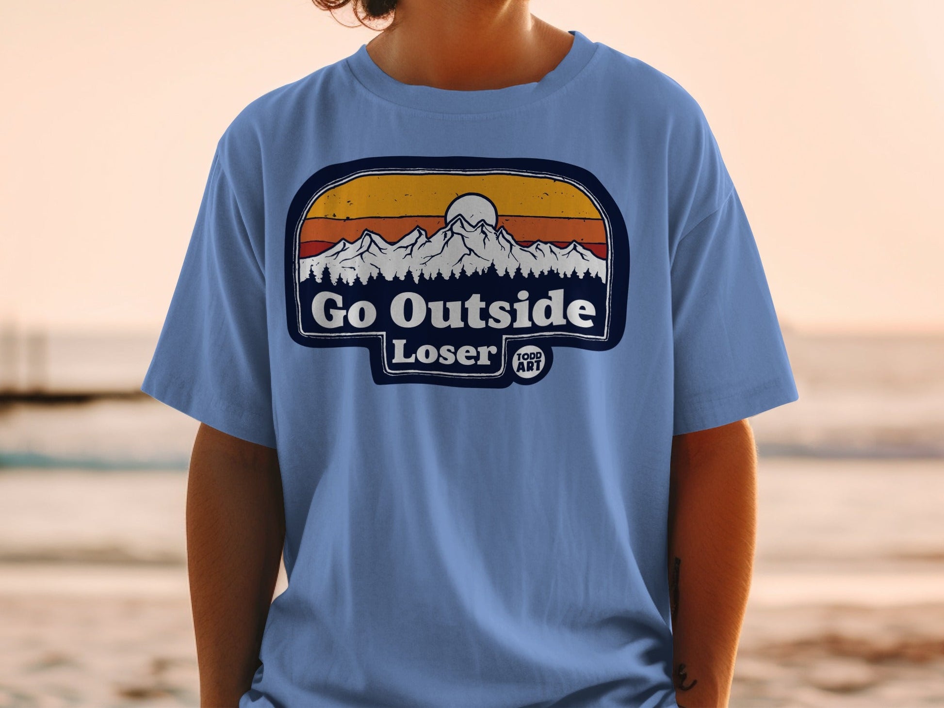 T-shirt with "Go Outside Loser" text and mountain sunset graphic.