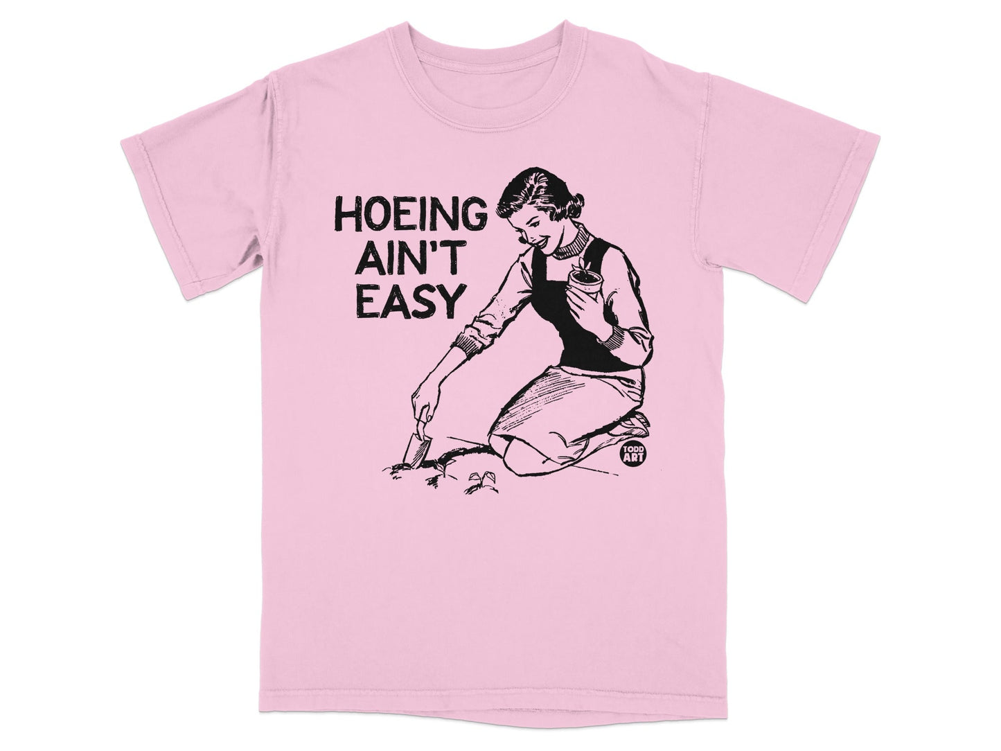 Pink t-shirt with black graphic of woman gardening and text "HOEING AIN'T EASY".
