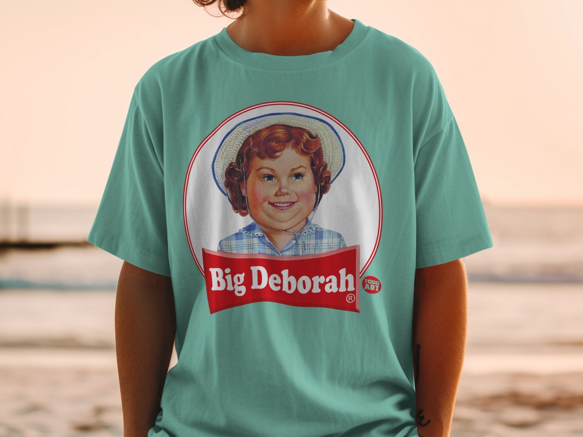 Child in straw hat on teal t-shirt with "Big Deborah" text.