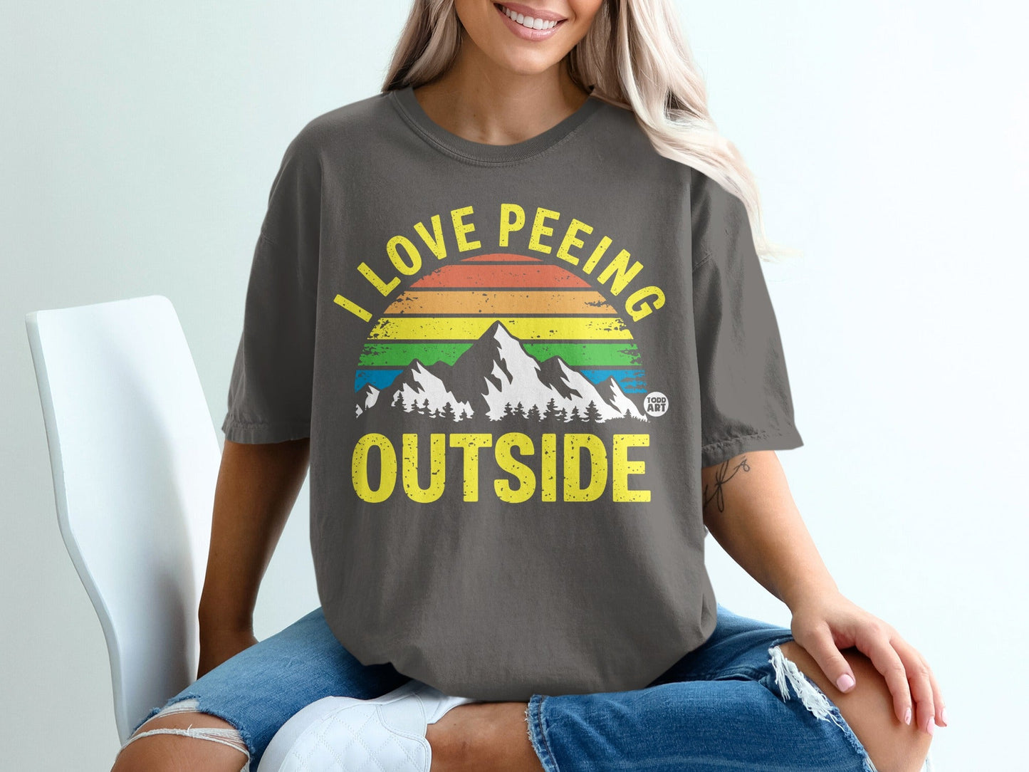 T-shirt with "I love peeing outside" and rainbow mountains graphic.