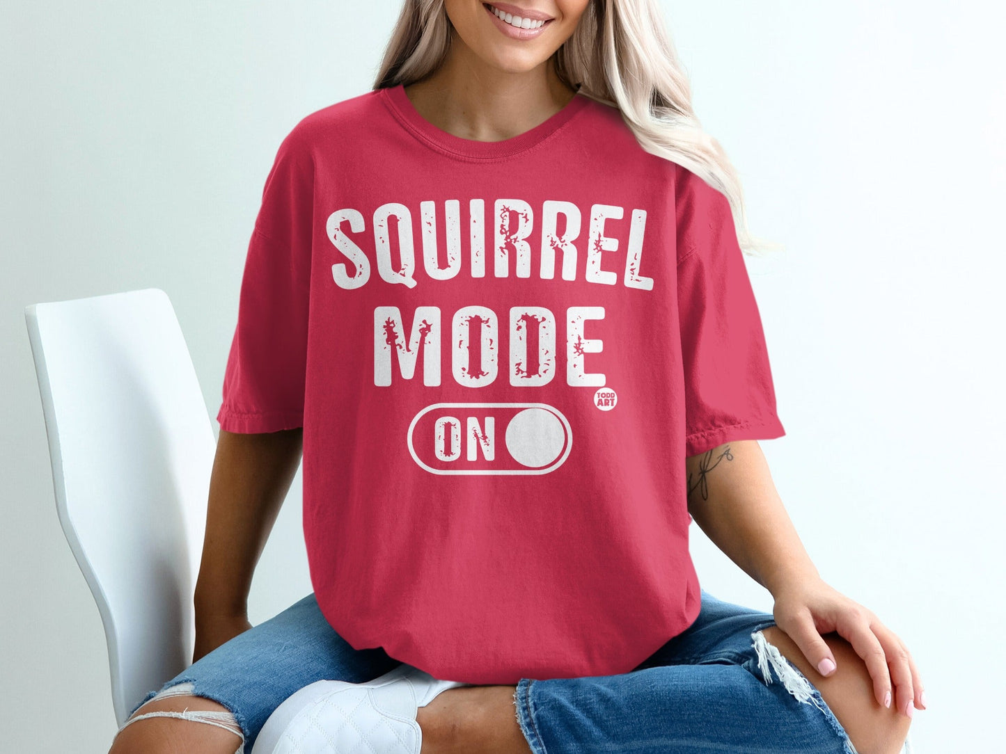 Red t-shirt with "SQUIRREL MODE ON" graphic and a small circular logo.