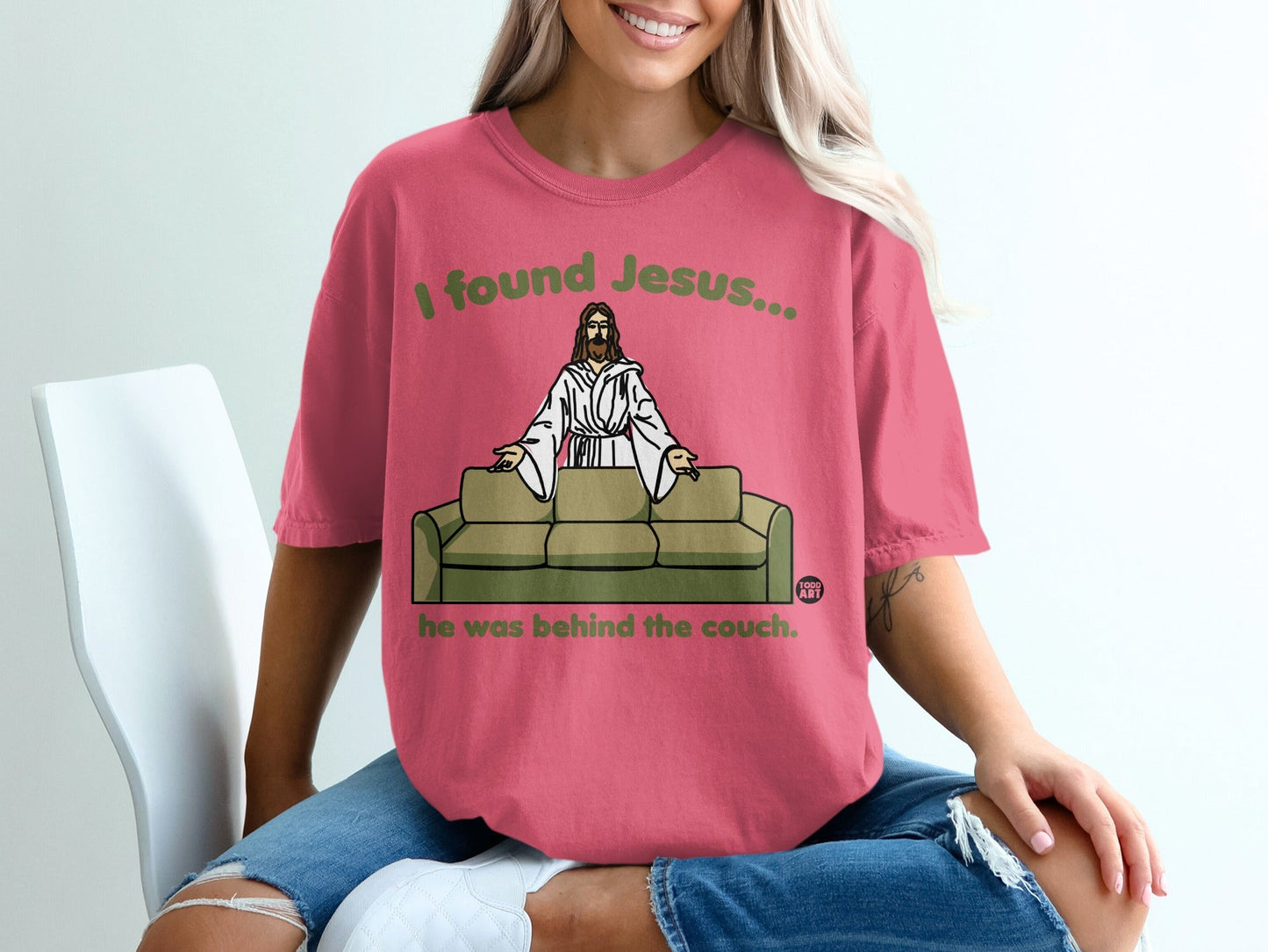 Pink t-shirt with Jesus on a couch and text "I found Jesus... he was behind the couch."
