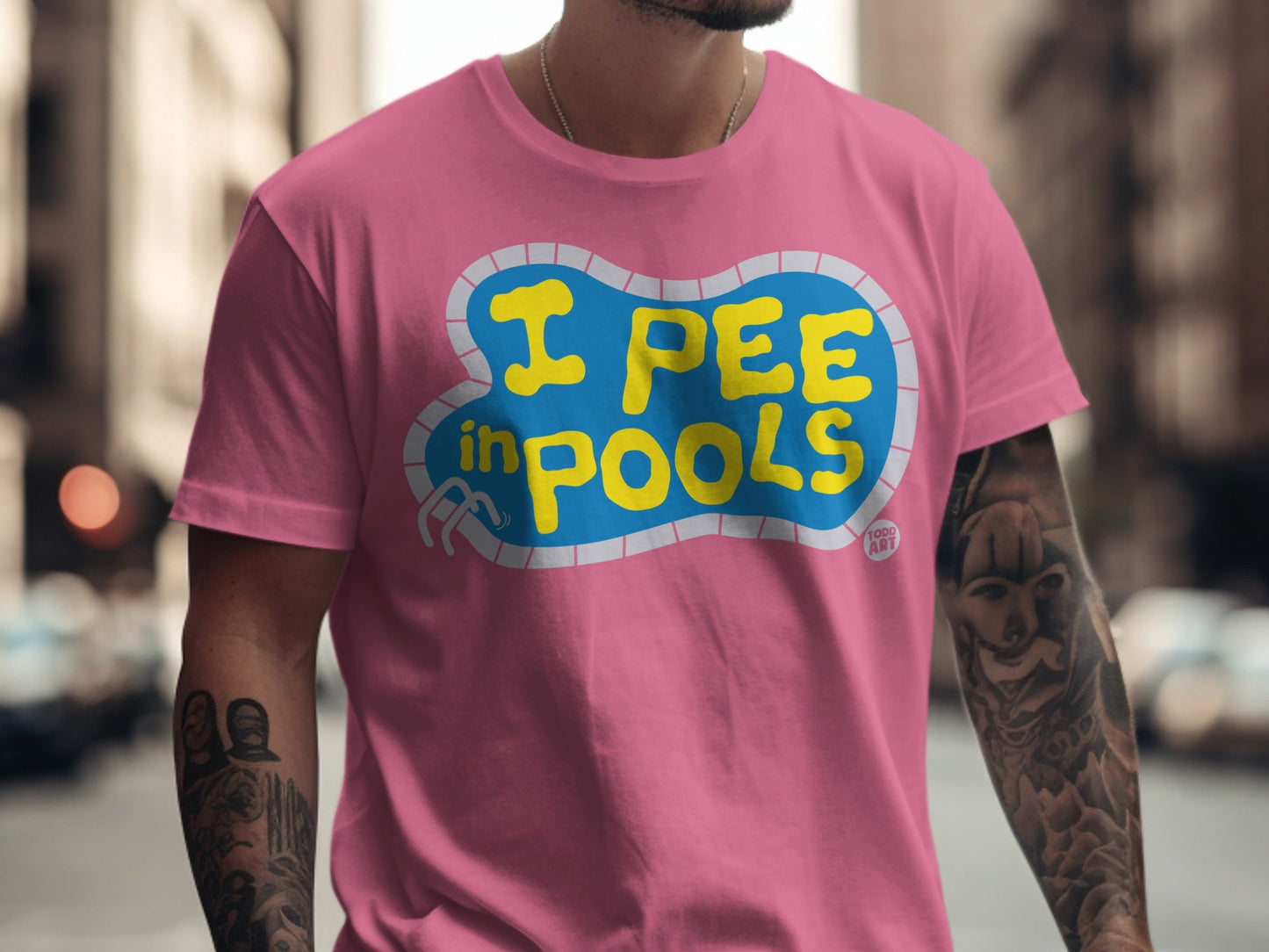 Pink t-shirt with "I PEE IN POOLS" text in yellow on a blue pool graphic.