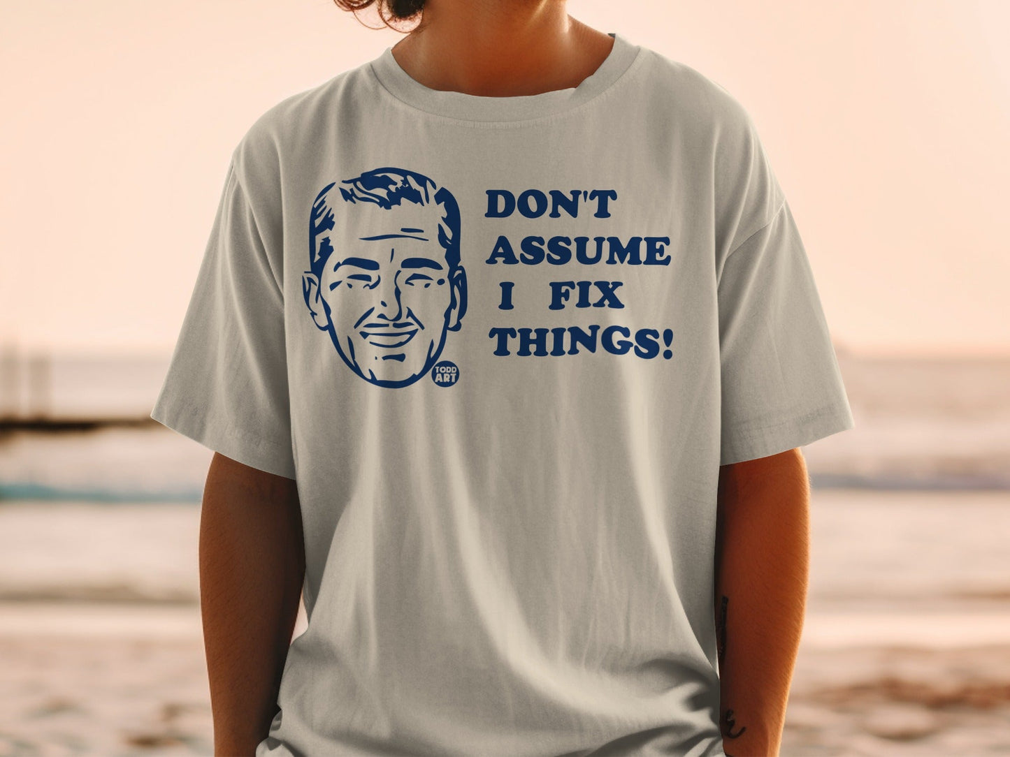 Light grey t-shirt with navy blue text and graphic: "Don't Assume I Fix Things!"
