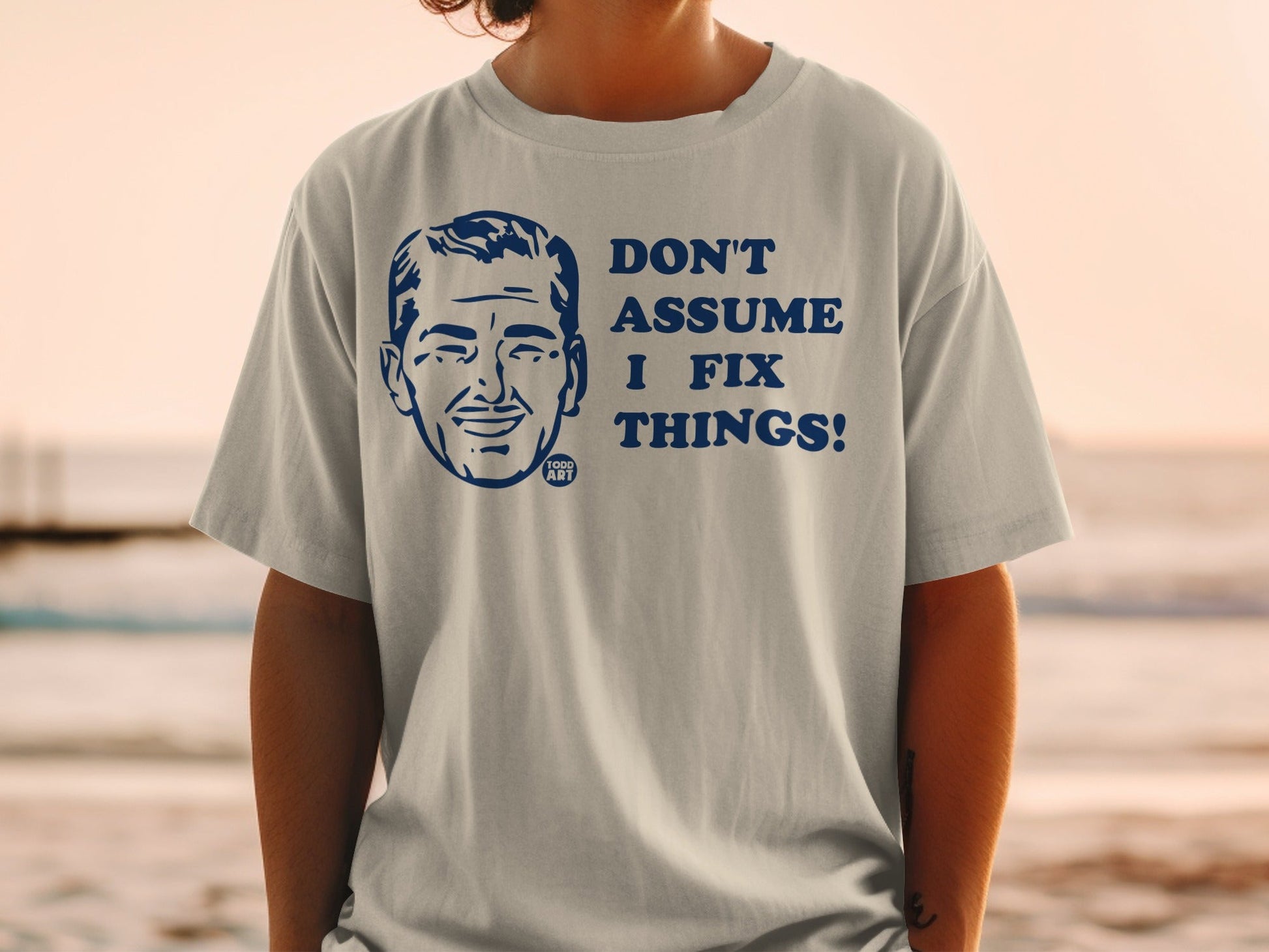 Light grey t-shirt with navy blue text and graphic: "Don't Assume I Fix Things!"