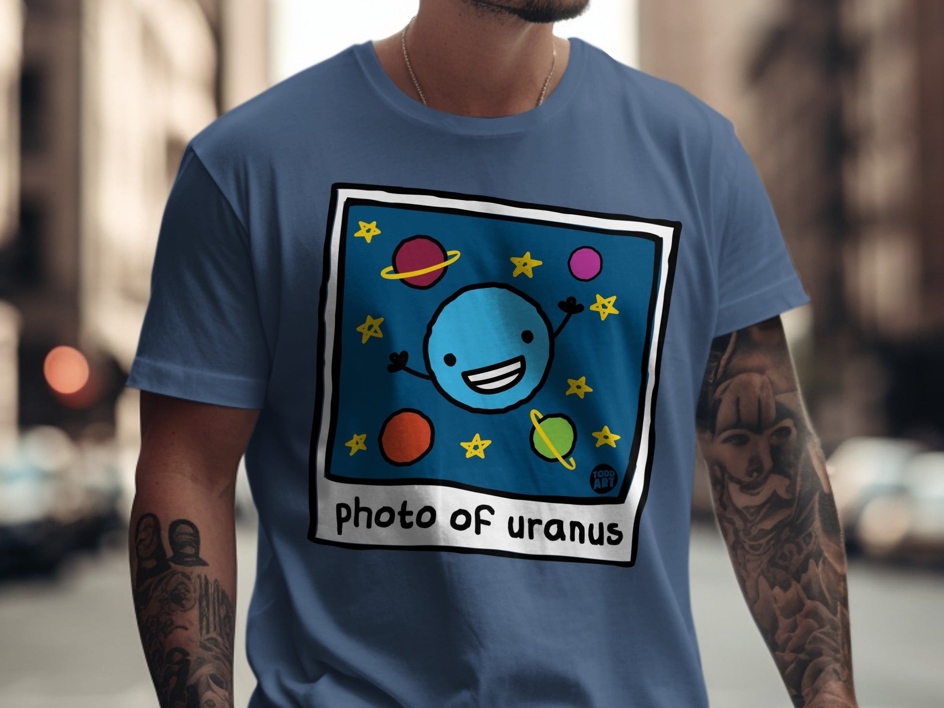 Blue t-shirt with a cartoon drawing of Uranus and stars.