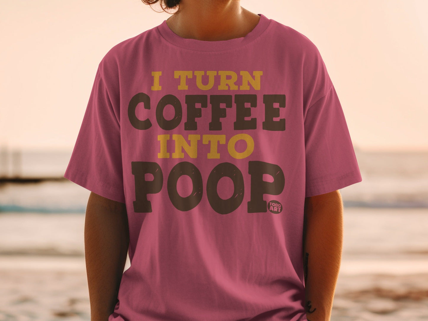 Pink t-shirt with yellow text that reads "I turn coffee into poop".
