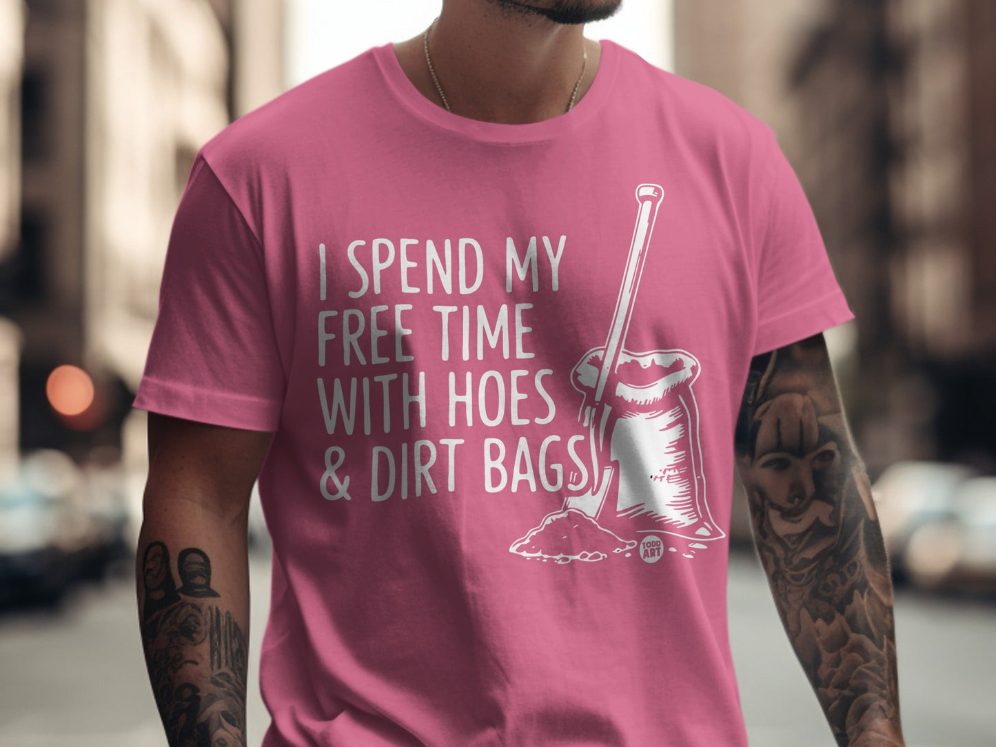 Pink t-shirt with "I spend my free time with hoes & dirt bags" text and shovel illustration.