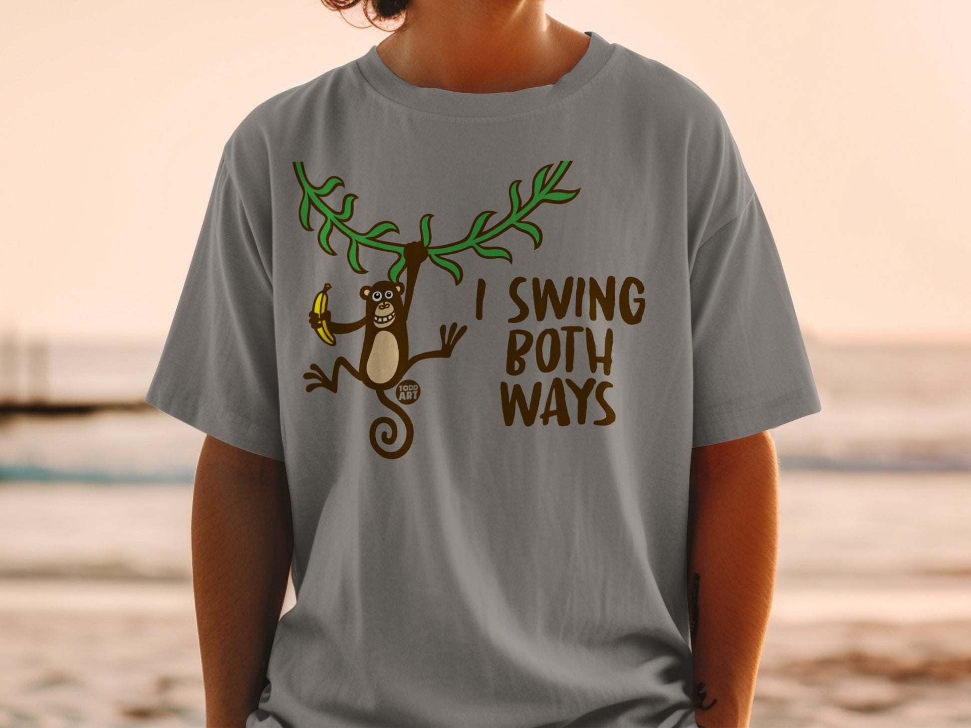 T-shirt with monkey hanging from vine, holding banana, text reads "I swing both ways".
