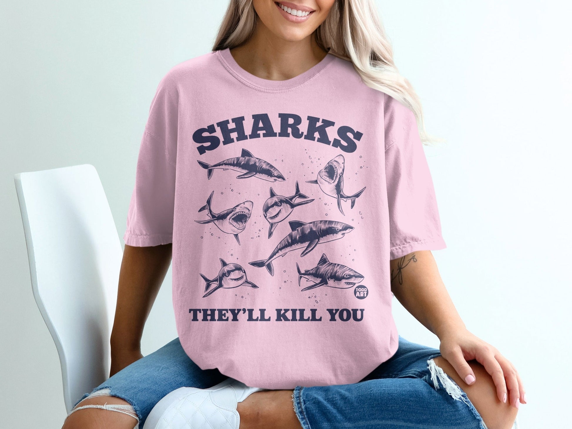 Pink t-shirt with "SHARKS THEY'LL KILL YOU" and illustrations of sharks.