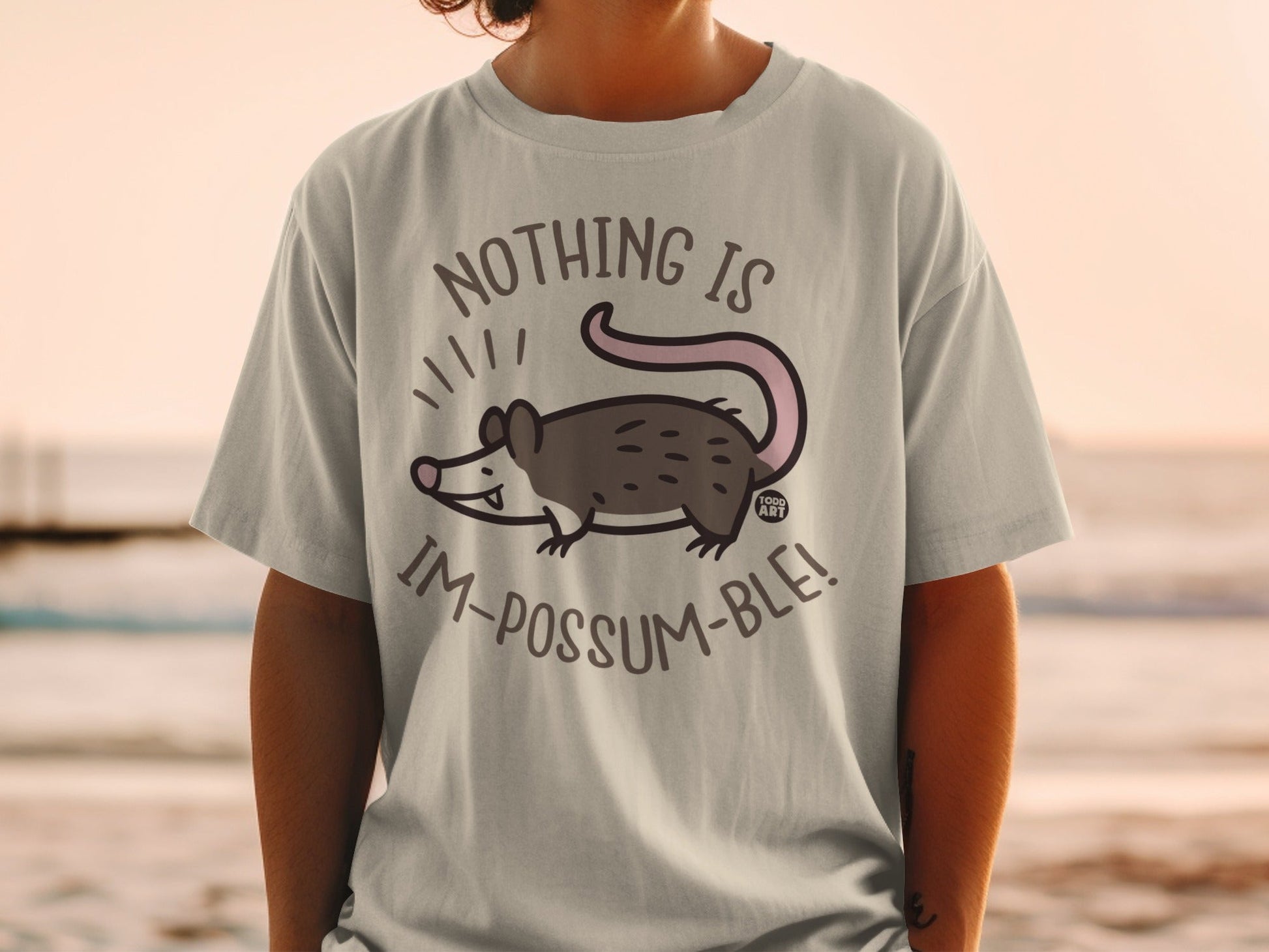 Light gray t-shirt with a cartoon possum and text "NOTHING IS IM-POSSUM-BLE!".