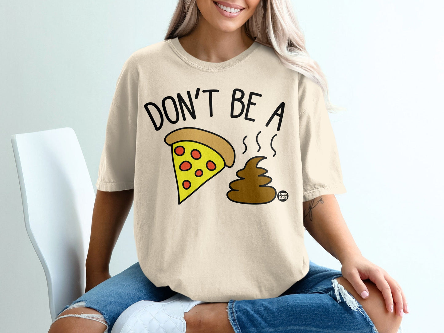 Cream t-shirt with pizza slice and brown emoji, text "DON'T BE A".