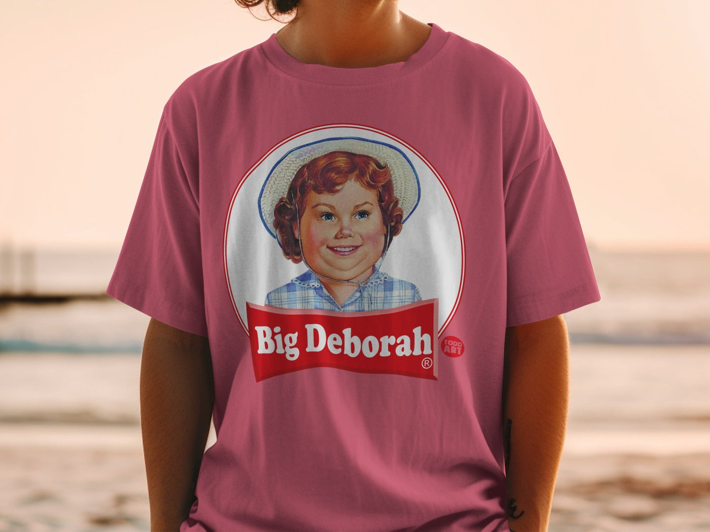 Pink t-shirt featuring a retro graphic of a smiling girl named Big Deborah.