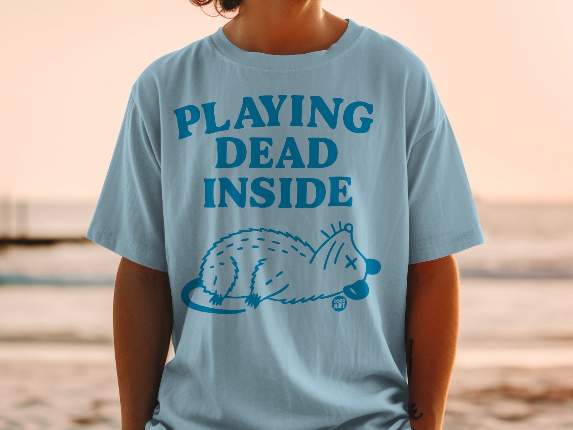Light blue t-shirt with "PLAYING DEAD INSIDE" and a possum graphic.