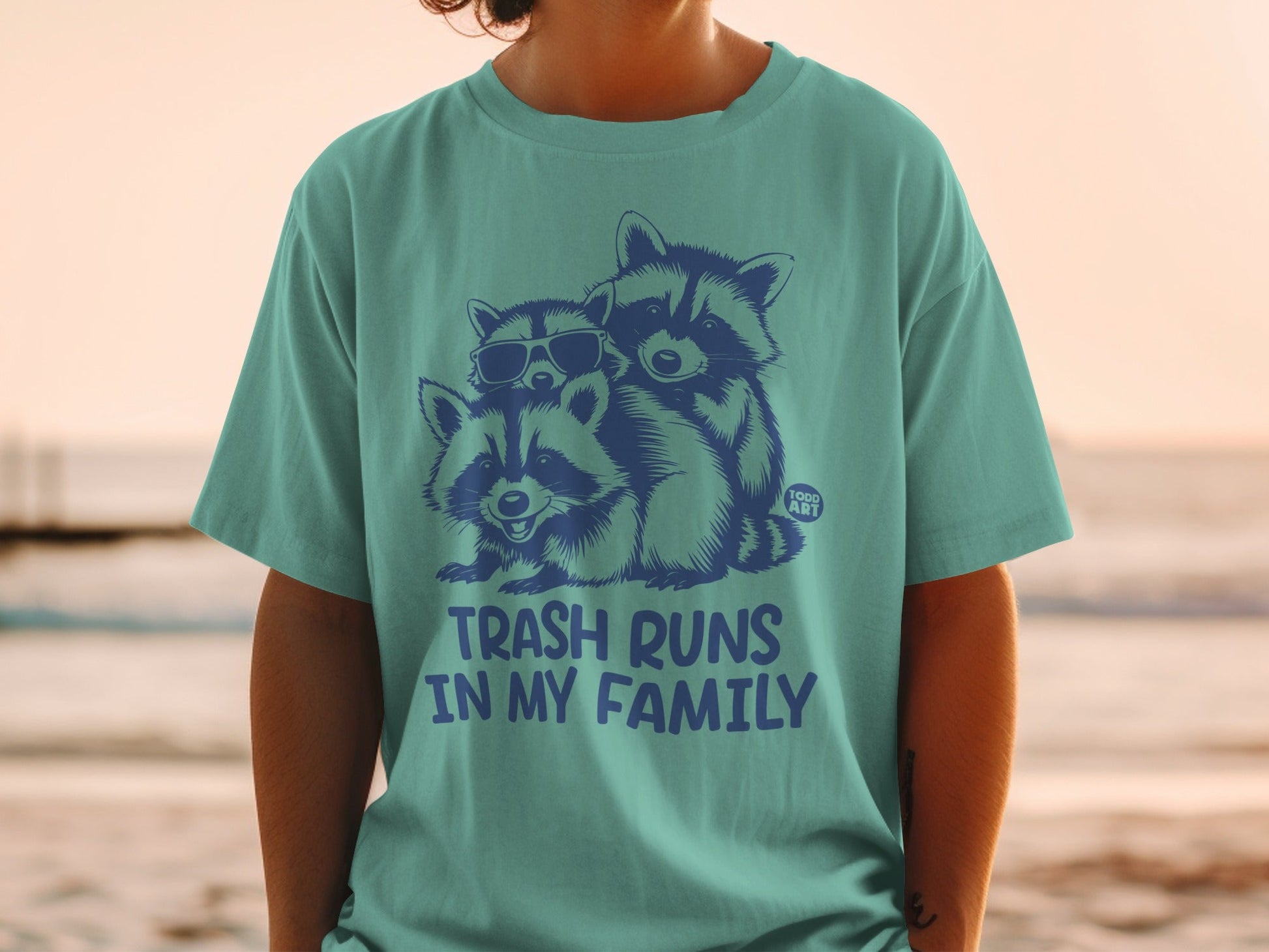 T-shirt with three raccoons wearing sunglasses, text "TRASH RUNS IN MY FAMILY".