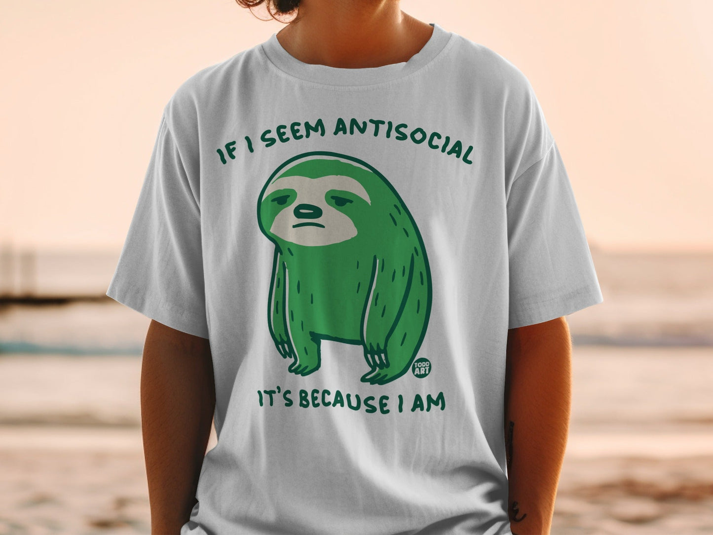 Green sloth graphic on a white t-shirt with text "IF I SEEM ANTISOCIAL IT'S BECAUSE I AM".