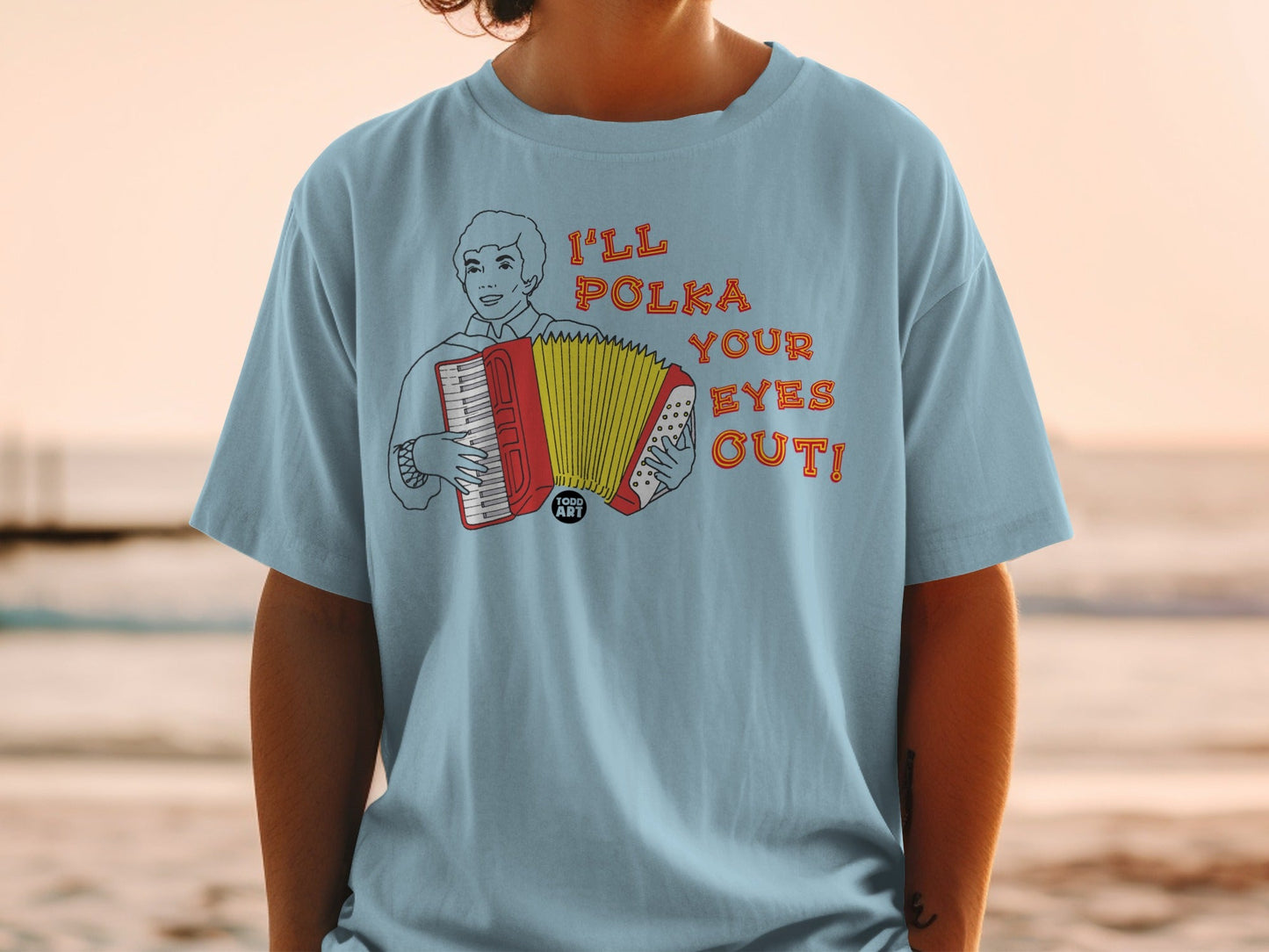 Light blue t-shirt with a cartoon man playing an accordion, text "I'LL POLKA YOUR EYES OUT!".