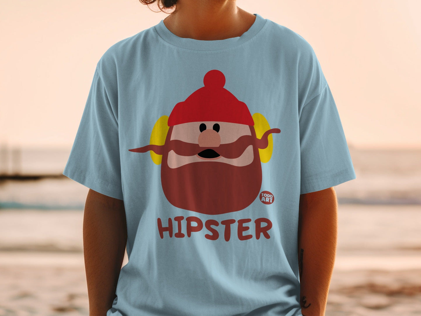 Light blue t-shirt with cartoon hipster character wearing red hat and earmuffs.