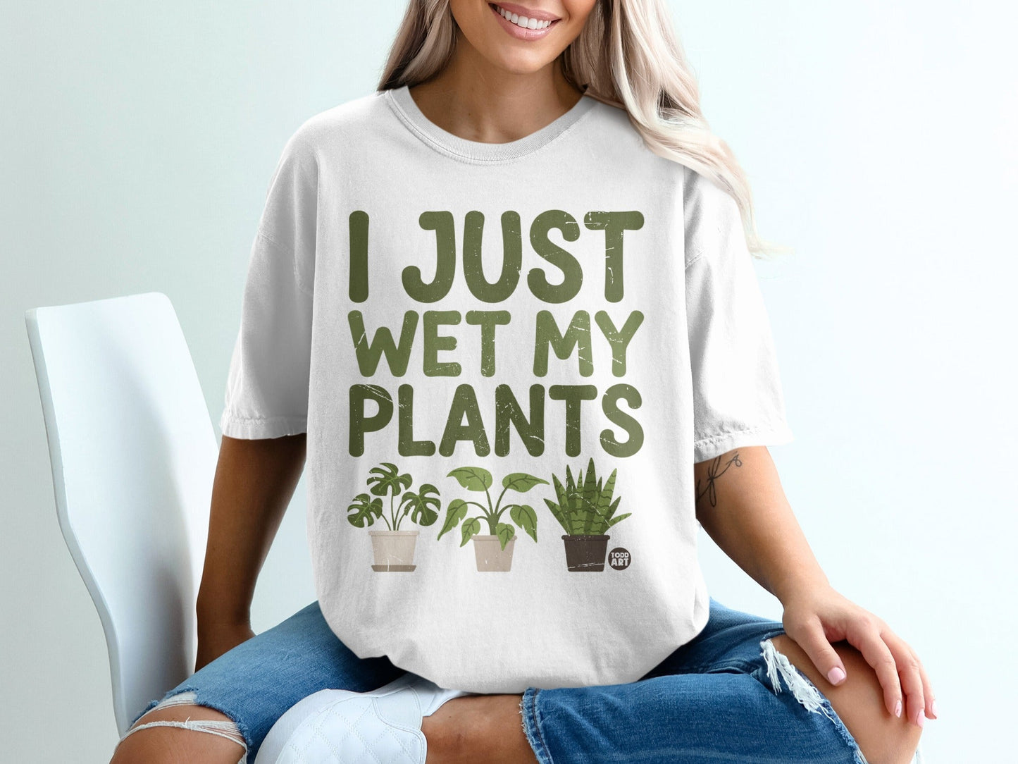 White t-shirt with "I JUST WET MY PLANTS" and three potted plants.