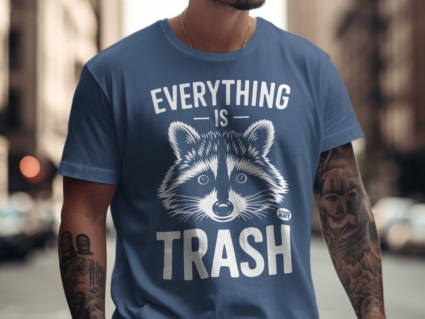 Blue t-shirt with a raccoon illustration and text "EVERYTHING IS TRASH".