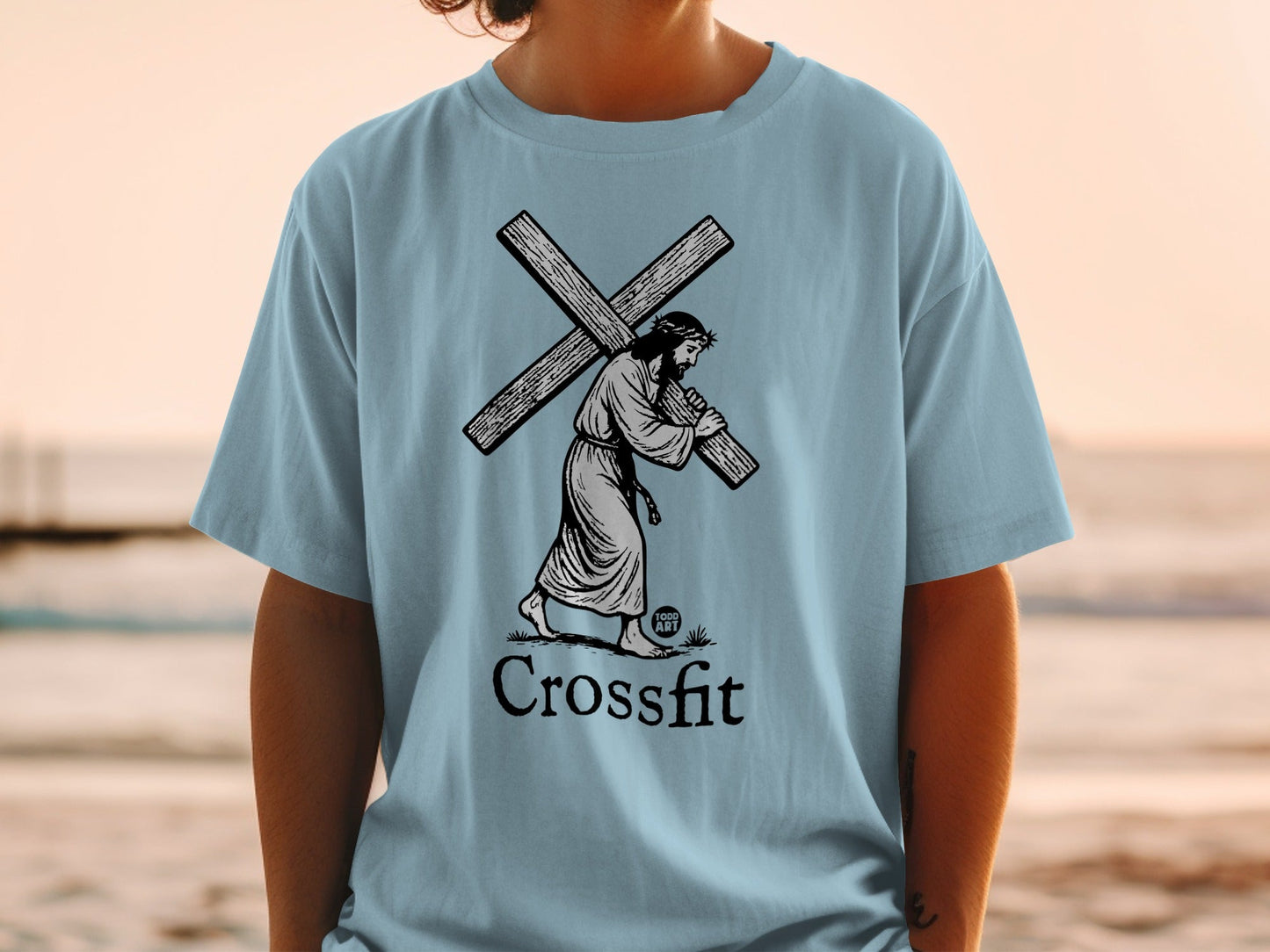 Jesus carrying a cross on a light blue t-shirt, with "CrossFit" text.