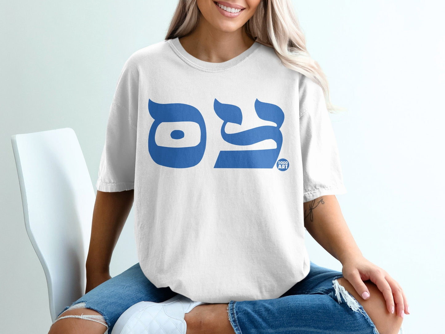 White t-shirt with large blue Hebrew letters "◊ò◊ï◊ì" (Todd) and "ART" logo.