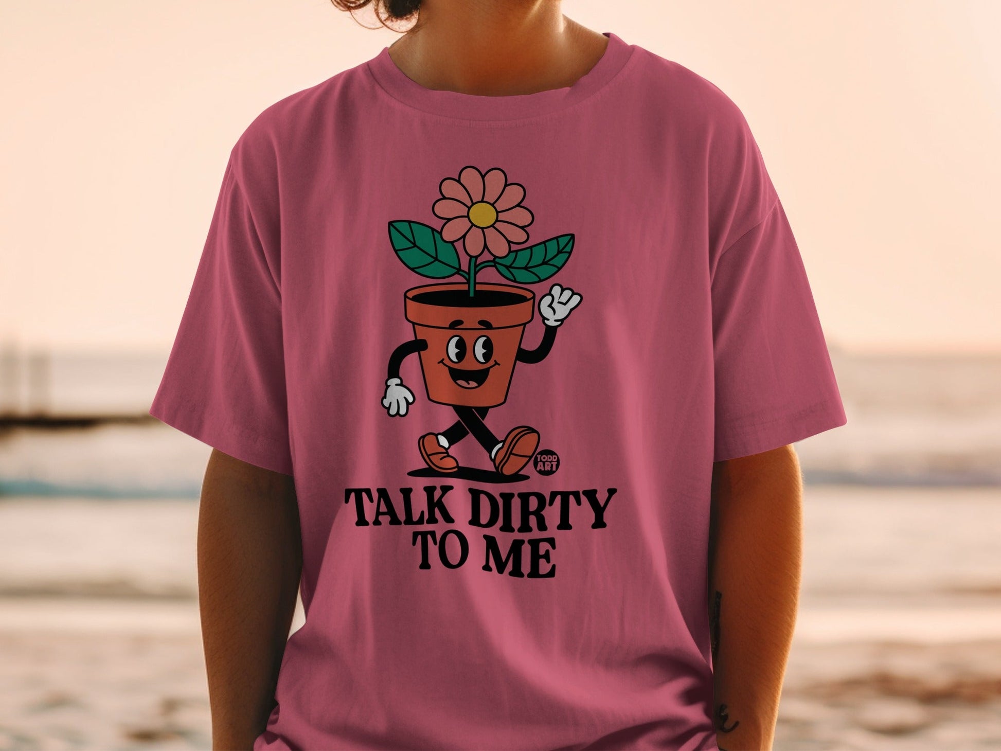 Pink t-shirt with a cartoon flower in a pot saying "Talk Dirty to Me."
