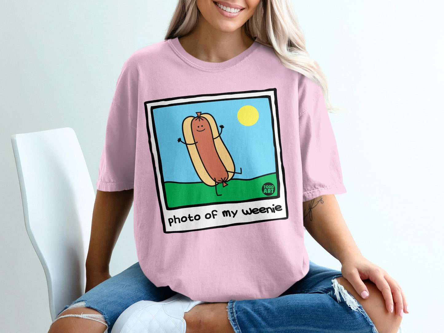 Pink t-shirt featuring a cartoon hot dog in a picture frame.