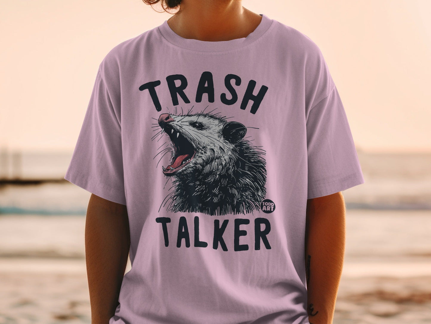 Purple t-shirt with a graphic of an opossum with text "TRASH TALKER".