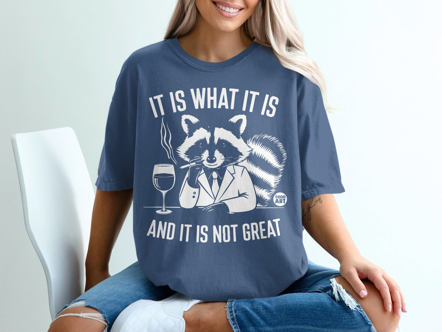 T-shirt with raccoon in suit smoking, holding wine glass, text "It is what it is".