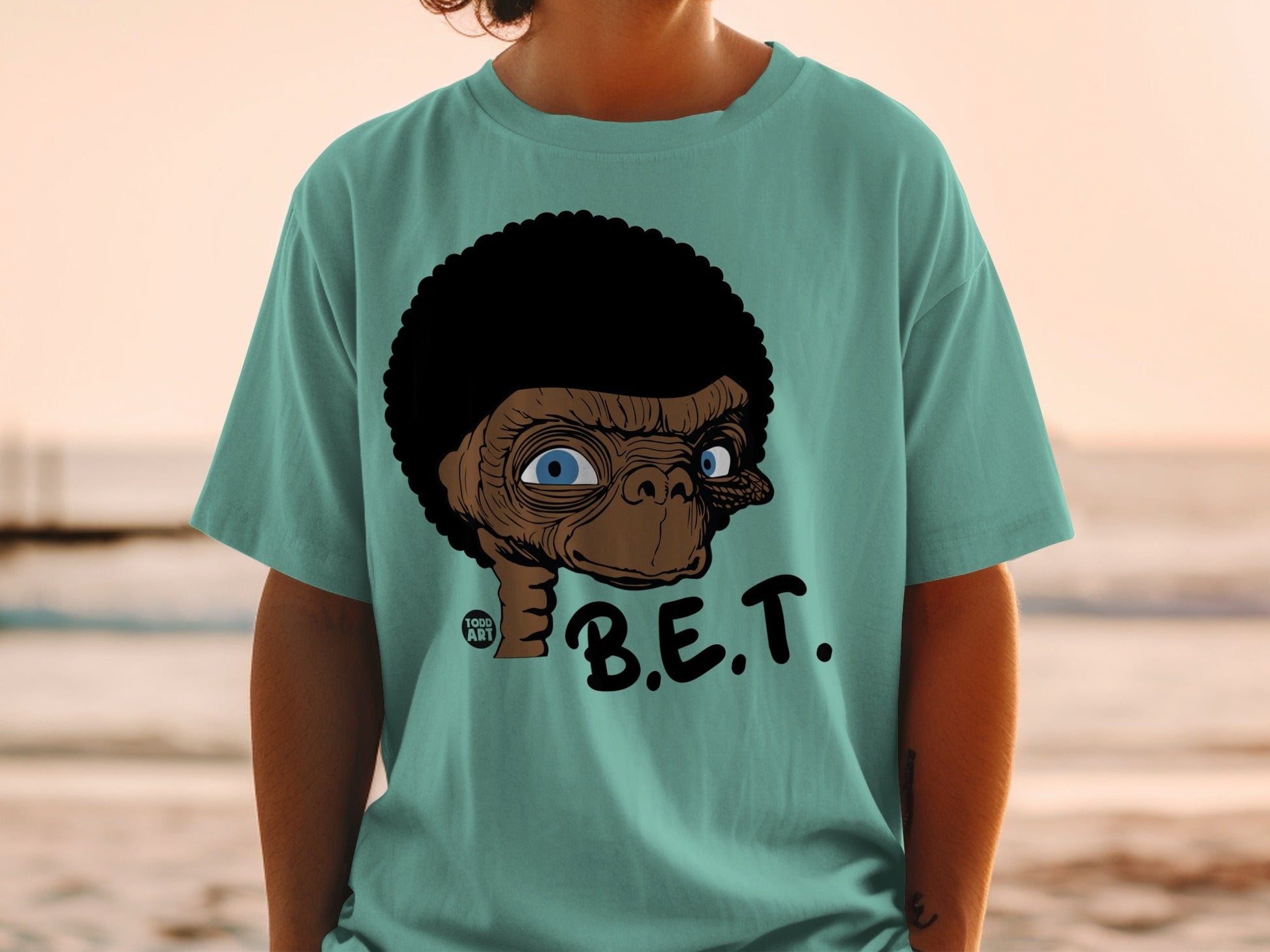 E.T. caricature on a teal t-shirt with "B.E.T." text.