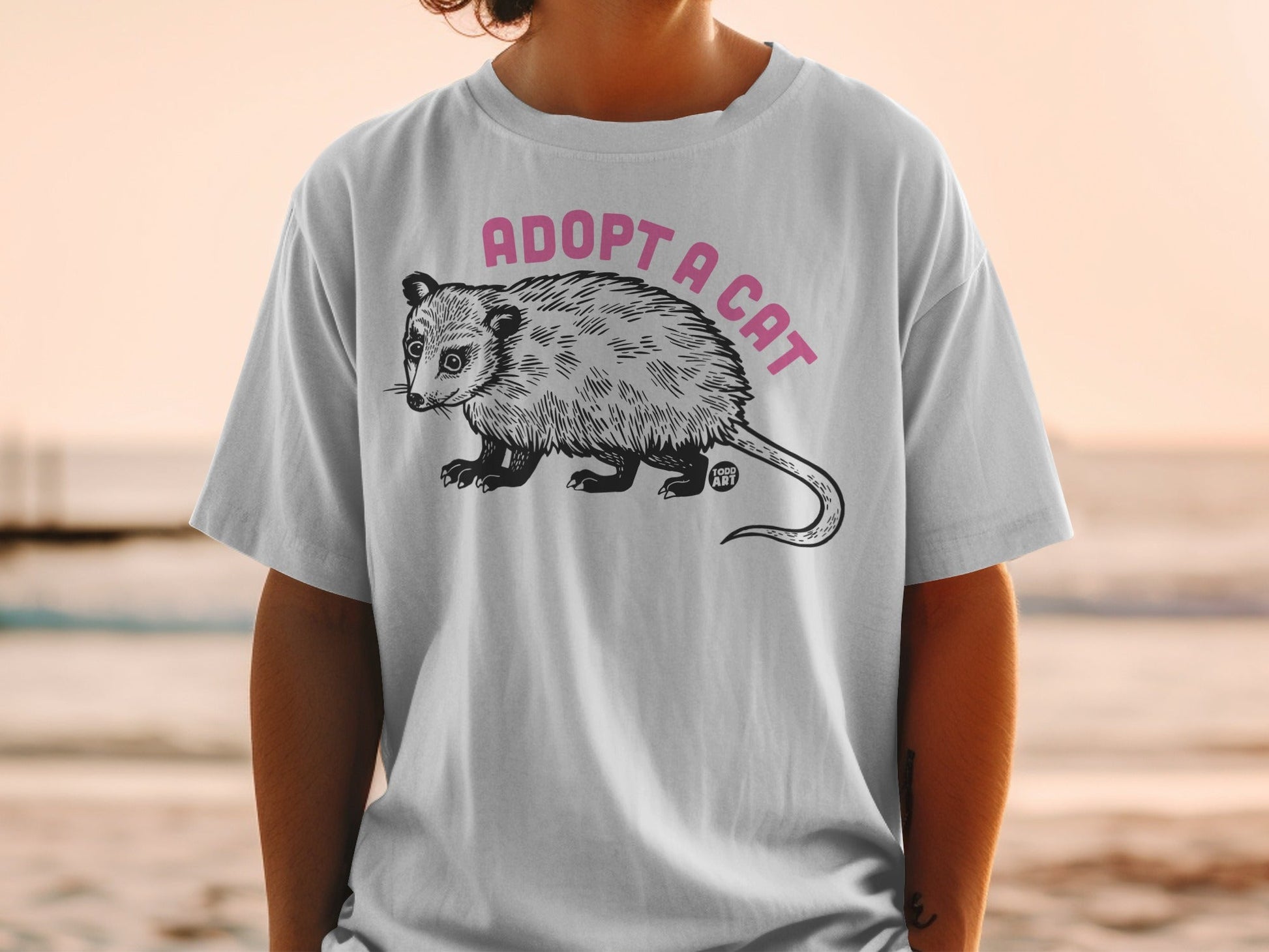 T-shirt with a possum illustration and "ADOPT A CAT" text.