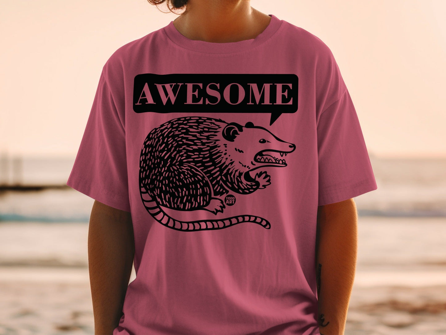 Pink t-shirt with illustration of a possum in a speech bubble saying "AWESOME".