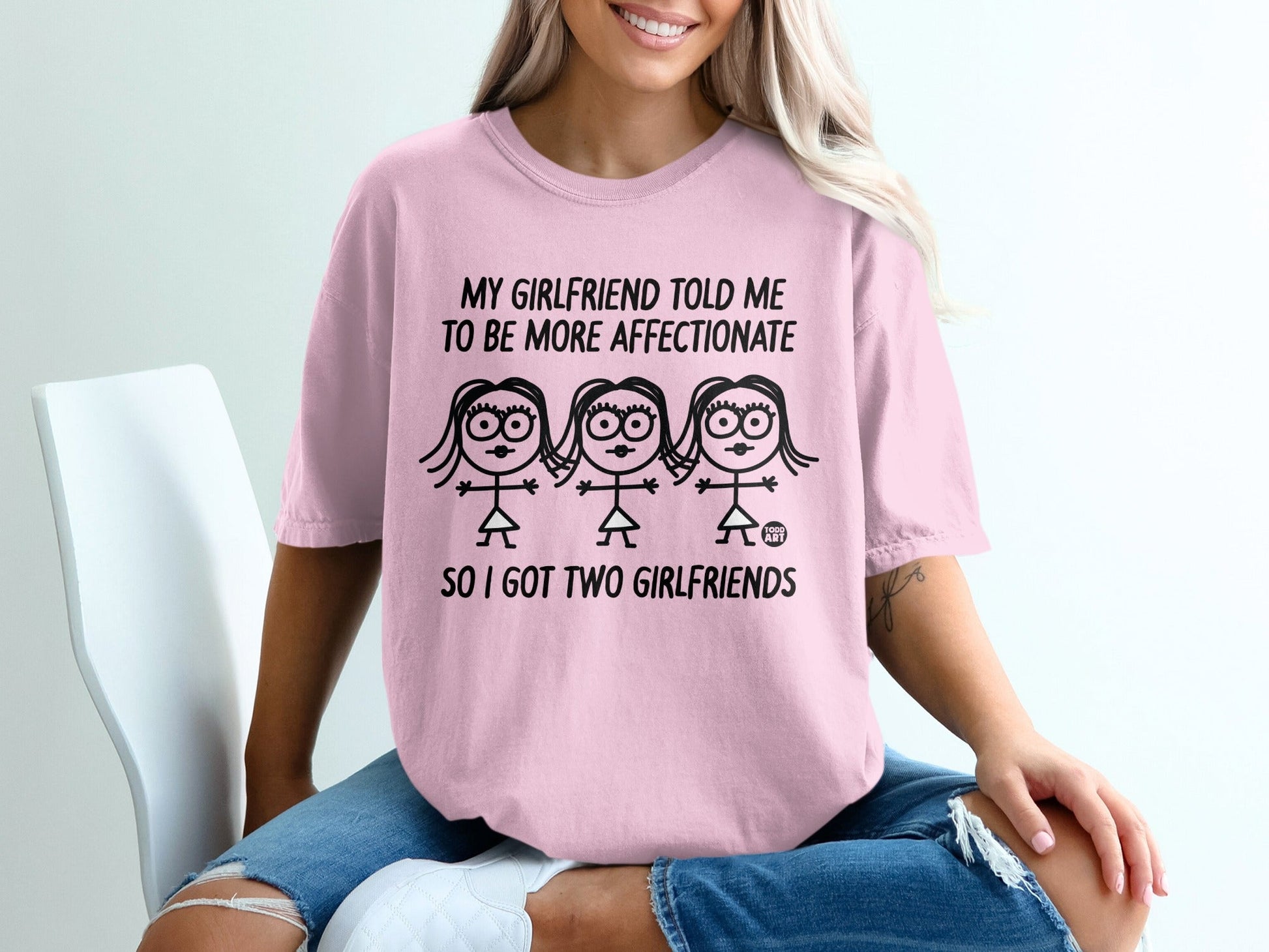 Pink t-shirt with cartoon women and text: "My girlfriend told me to be more affectionate, so I got two girlfriends."