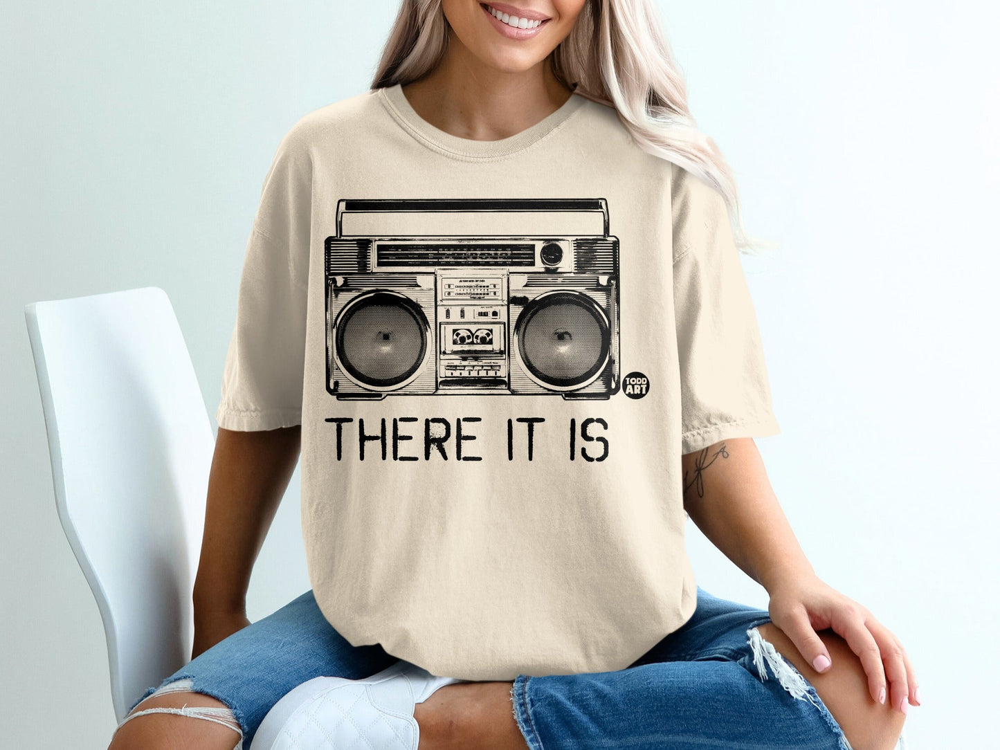 Cream t-shirt with black graphic of a boombox and "THERE IT IS" text.