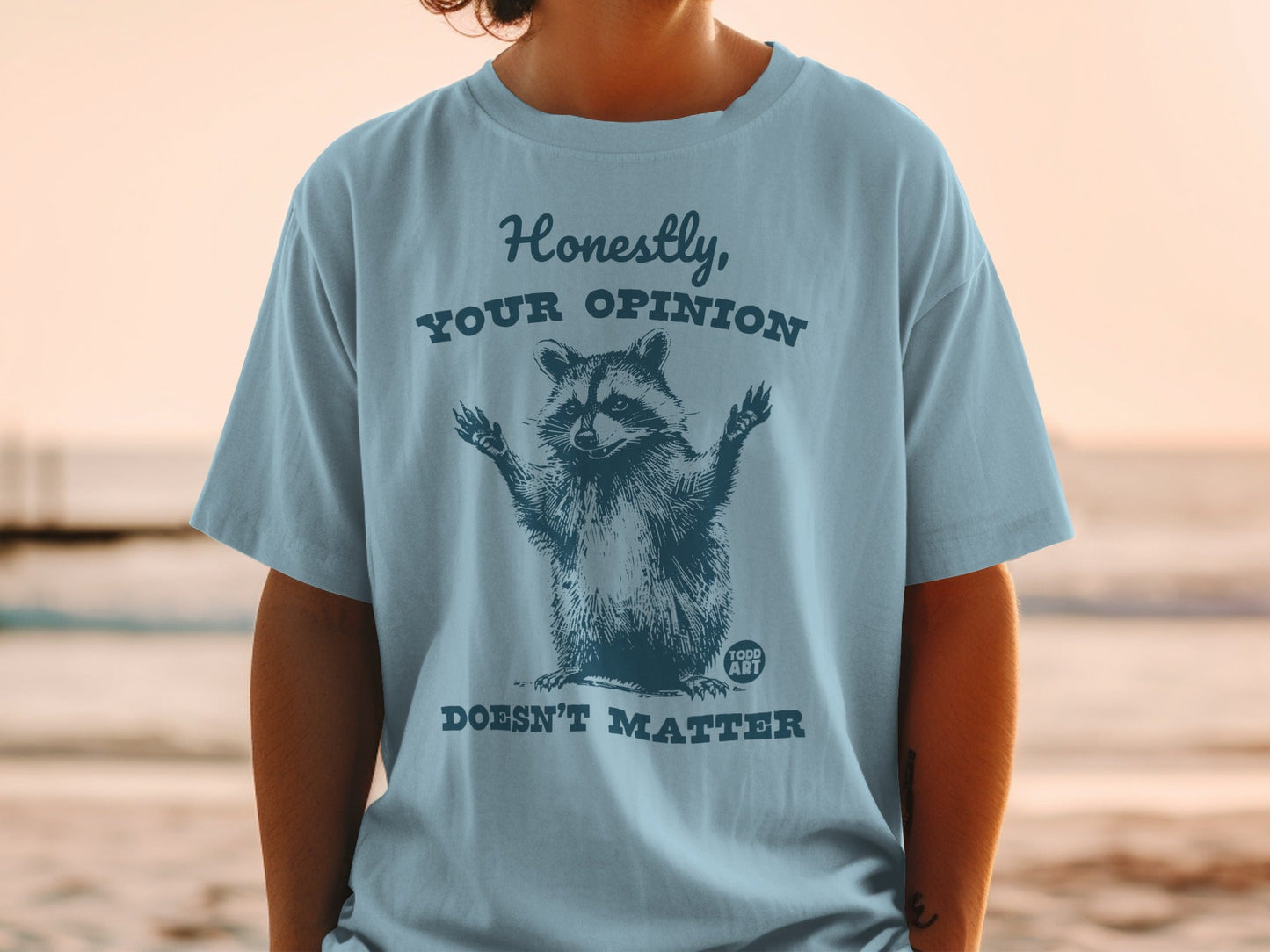 Blue t-shirt with raccoon graphic and text "Honestly, YOUR OPINION DOESN'T MATTER".