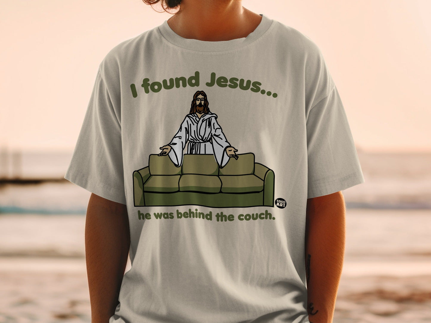 T-shirt with "I found Jesus... he was behind the couch" text and Jesus graphic.