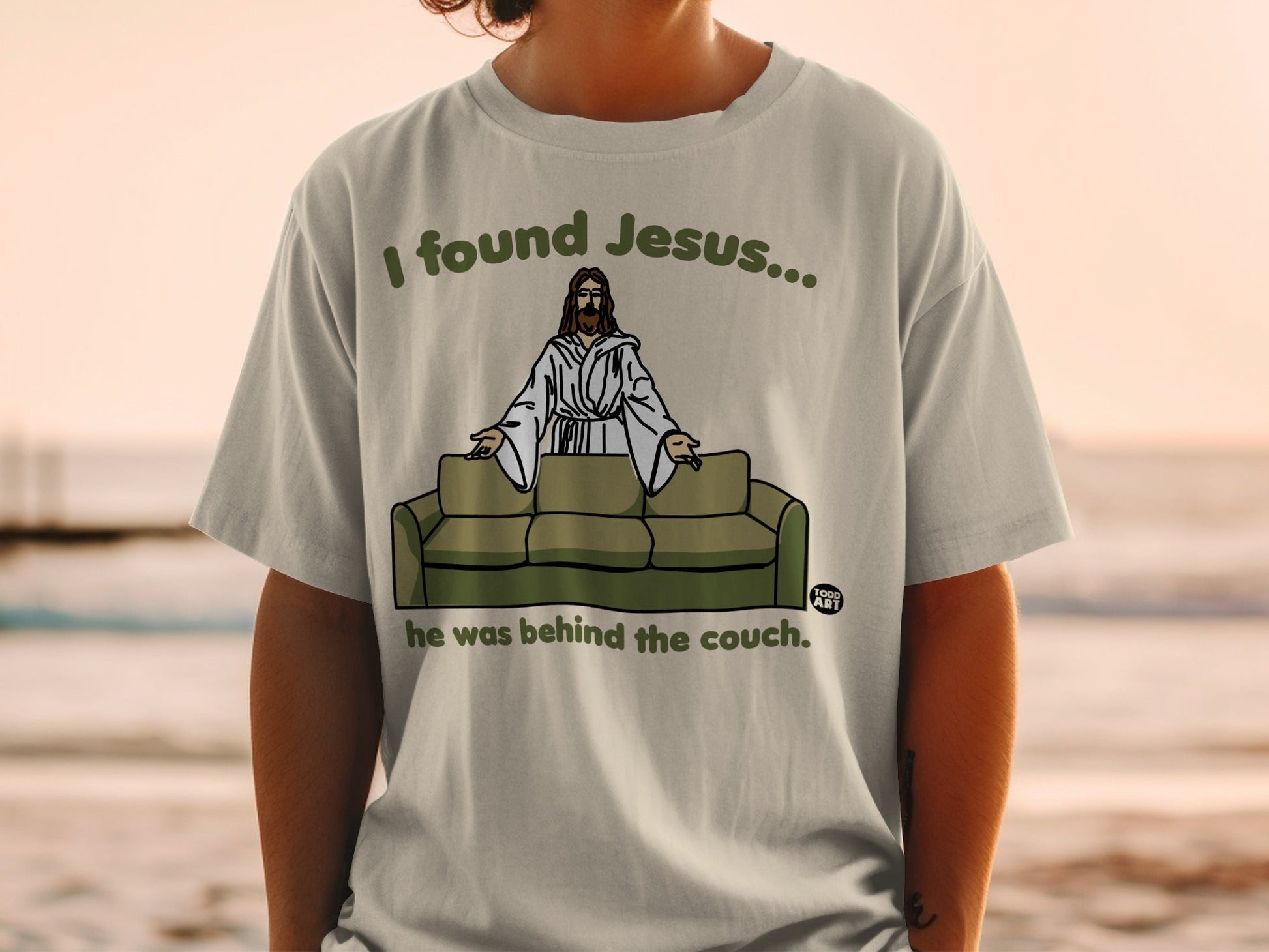 T-shirt with "I found Jesus... he was behind the couch" text and Jesus graphic.
