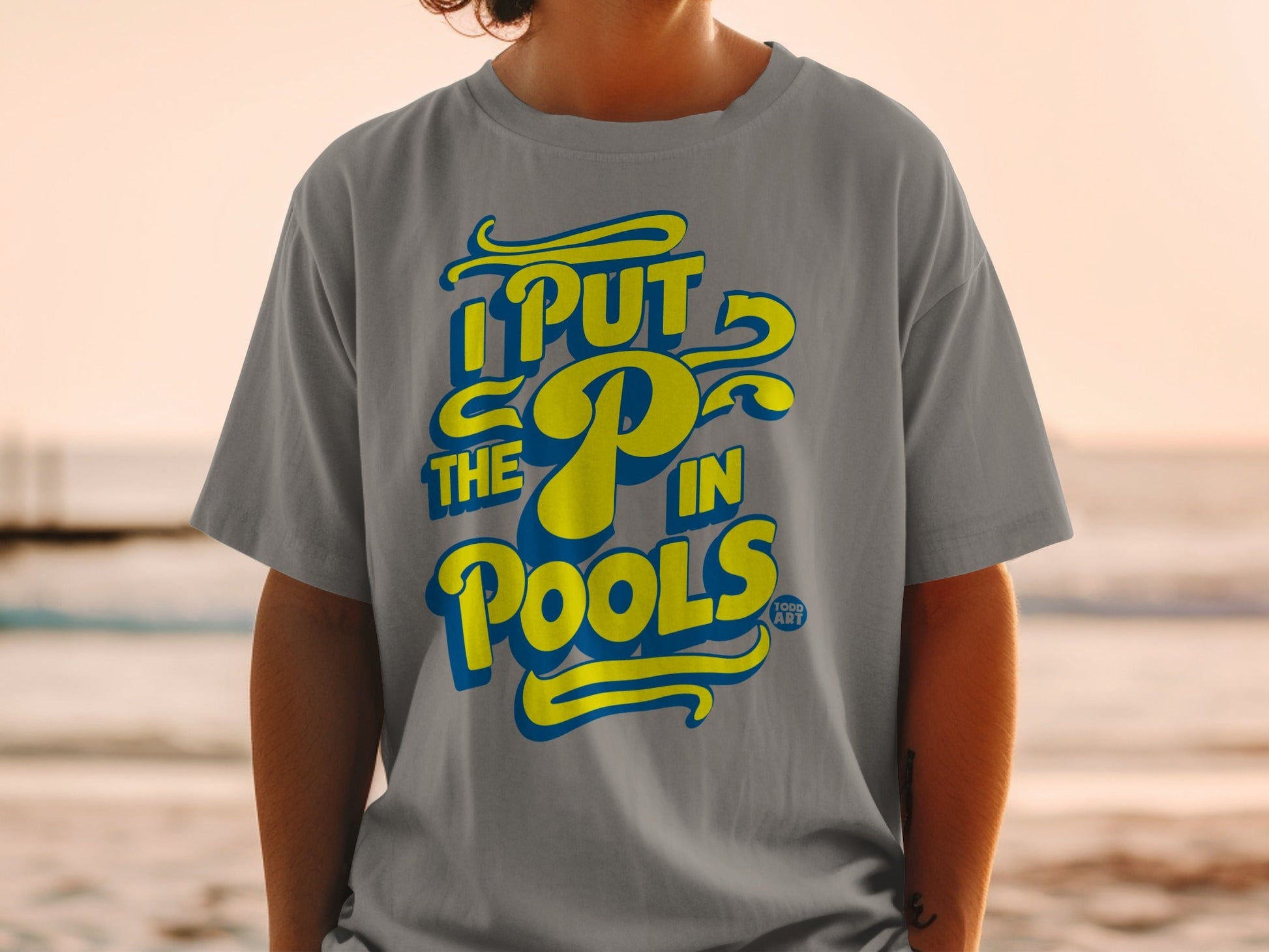 Grey t-shirt with yellow text reading "I PUT THE P IN POOLS".