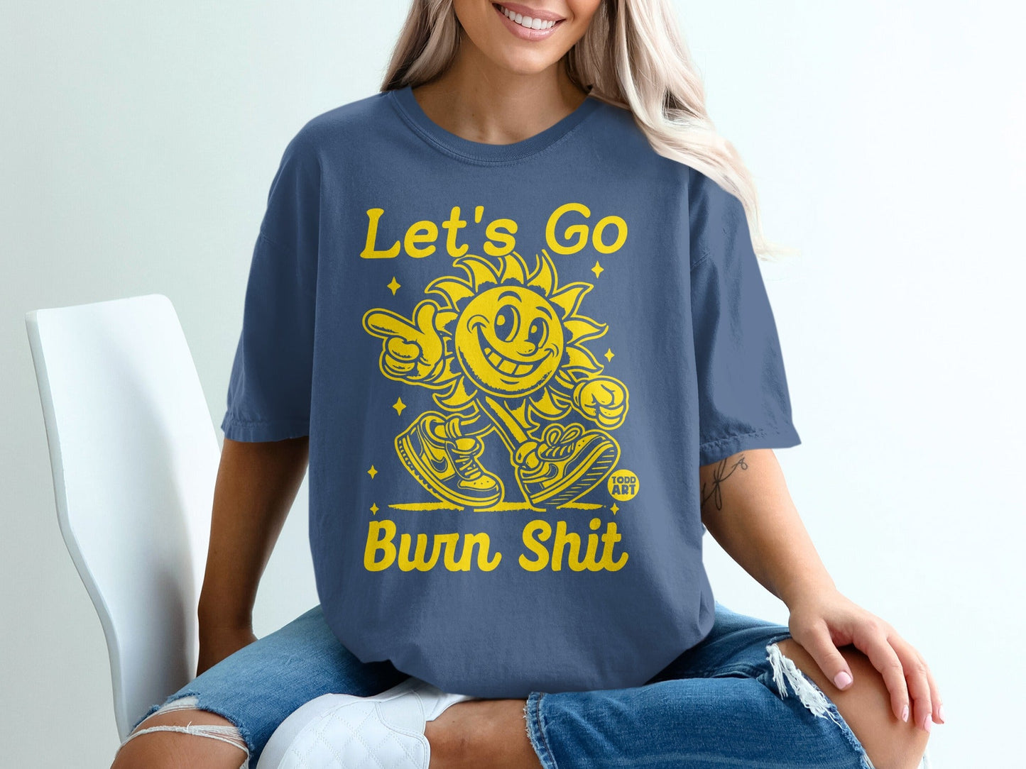Blue t-shirt with yellow text "Let's Go Burn Shit" and a cartoon sun.