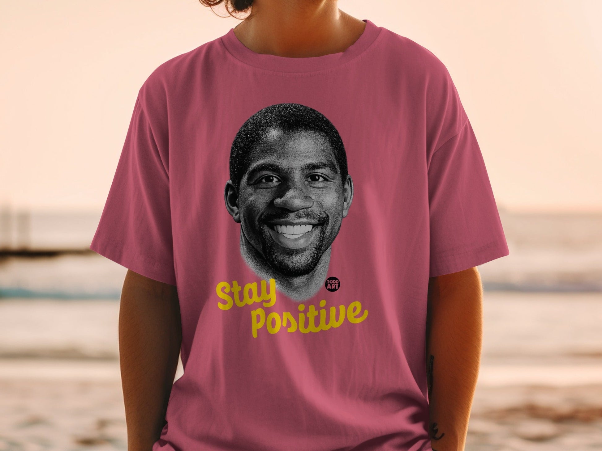 Pink t-shirt with portrait of Magic Johnson and "Stay Positive" text.