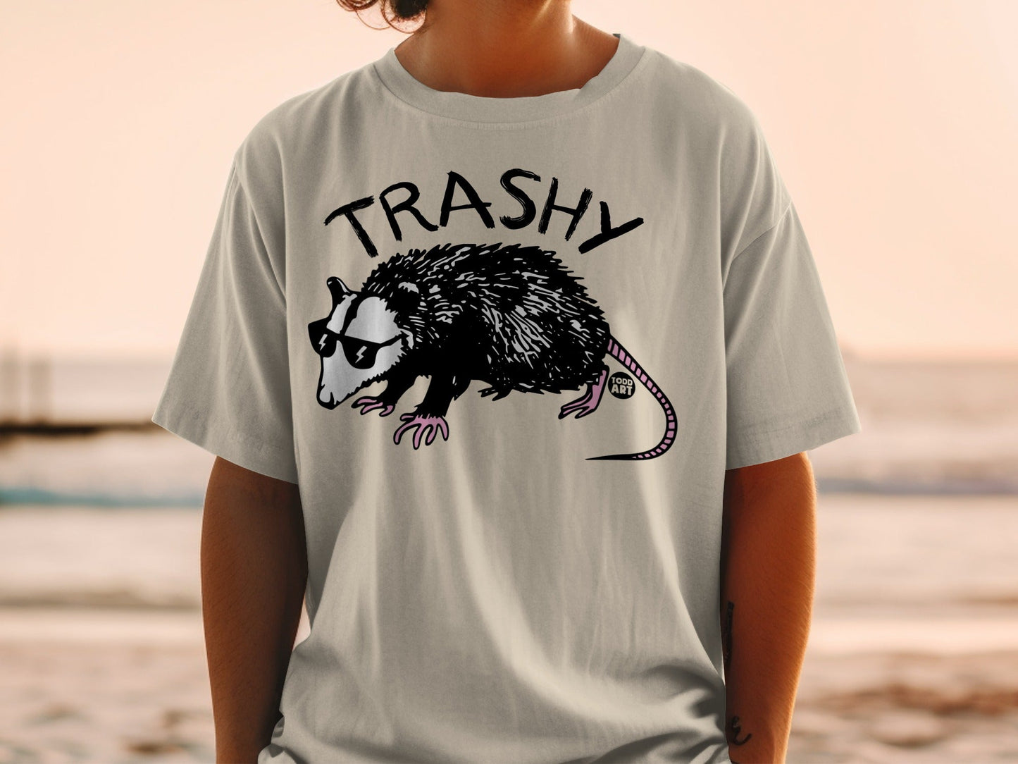 Grey t-shirt with a cartoon possum wearing sunglasses and a "TRASHY" logo.