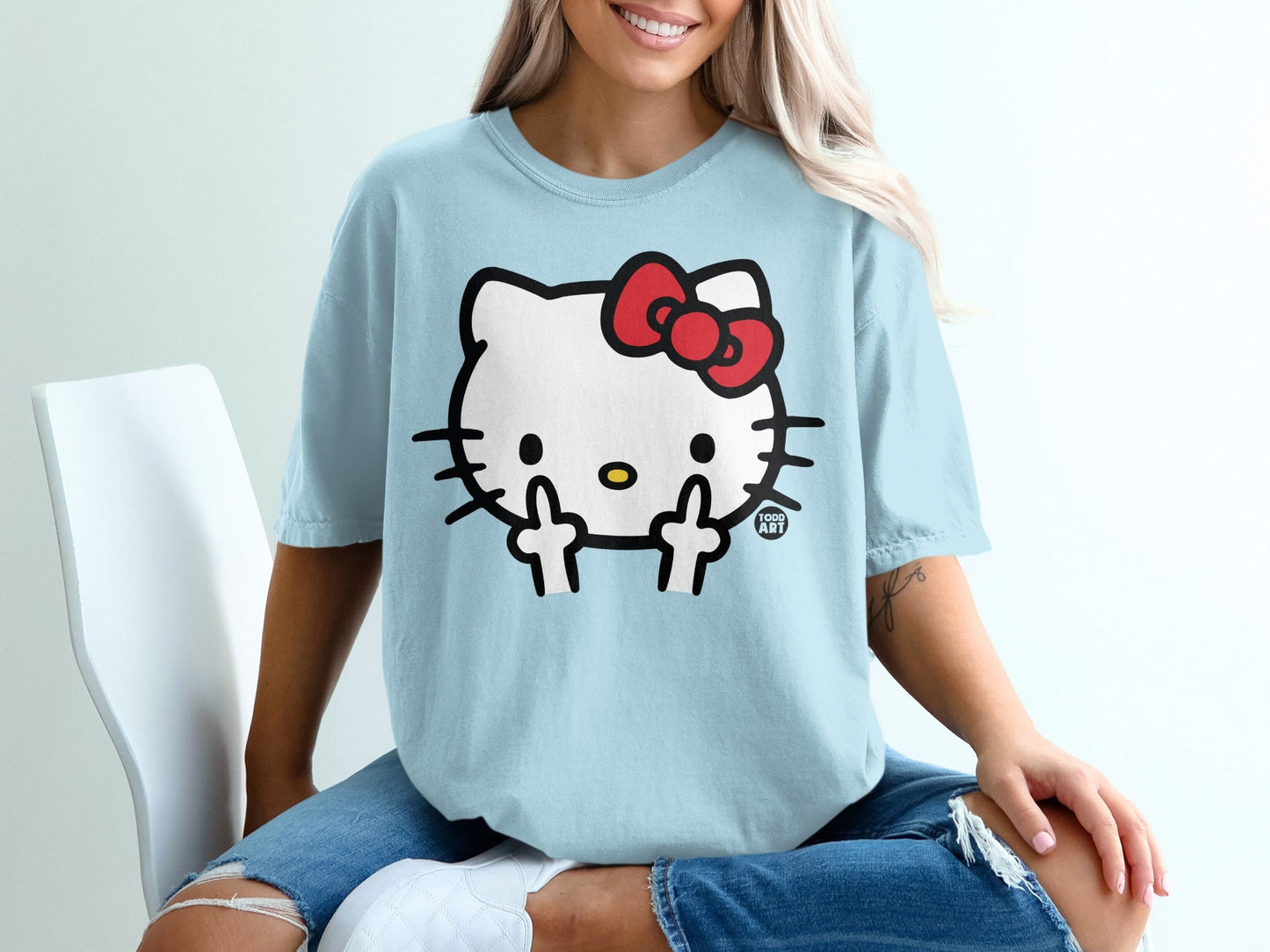 Light blue t-shirt featuring Hello Kitty with a red bow giving the middle finger.